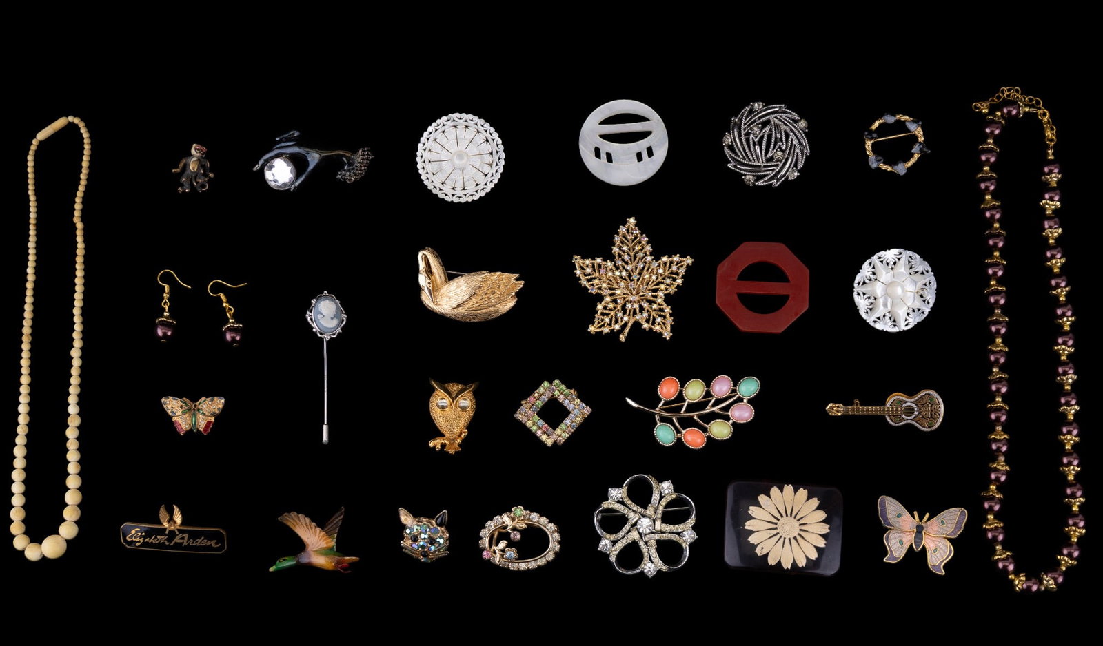 Designer, Mother of pearl, and Other Brooches: A collection of brooches and necklaces featuring dessigner brands such as Trifari, Lisner, and Sarah Coventry, and designs featuring a Spanish Damask guitar brooch, two carved mother of pearl brooches