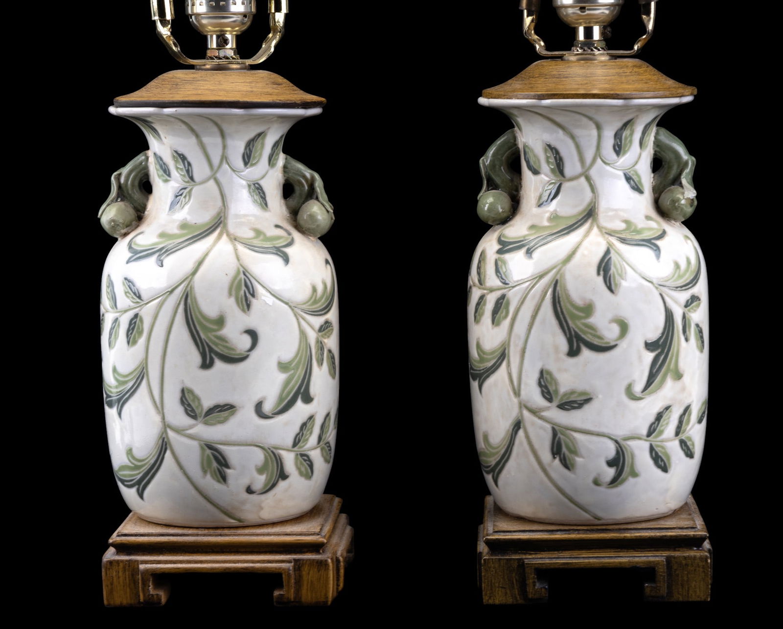 Vintage Chinese Lamp Pair: A pair of vintage Chinese lamps on wooden bases each standing approximately 19.5" to top of finnial. Body measuring approx. 10" on base. Note: Mismatched harps and finnials.