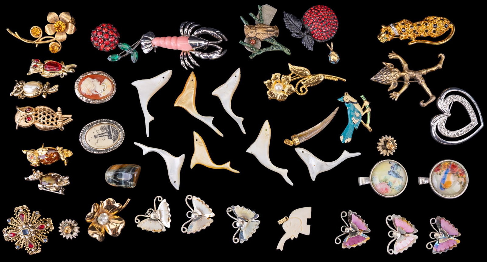 Brooches, Beads, and More: A collection of brooches and other jewelry including a rhinestone heart by Napier, owl pins by Gerry's and Trifari, a gold tone clover with rhinestone center by Coro, a heraldic Maltese cross brooch a