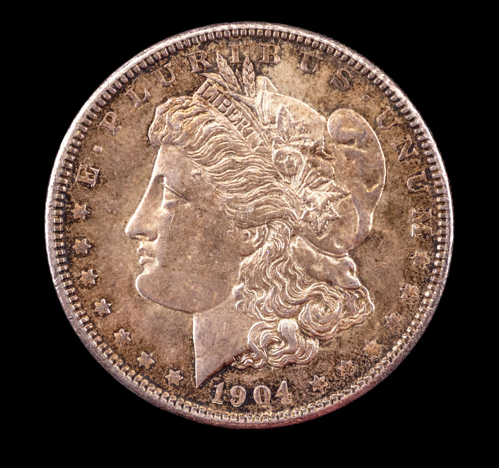 1904 United States Morgan Silver Dollar: 1904 United States Morgan Silver Dollar struck in 90% silver and 10% copper. The obverse displays a profile of Lady Liberty with a Phrygian cap and detailed hair, surrounded by stars and the mint year