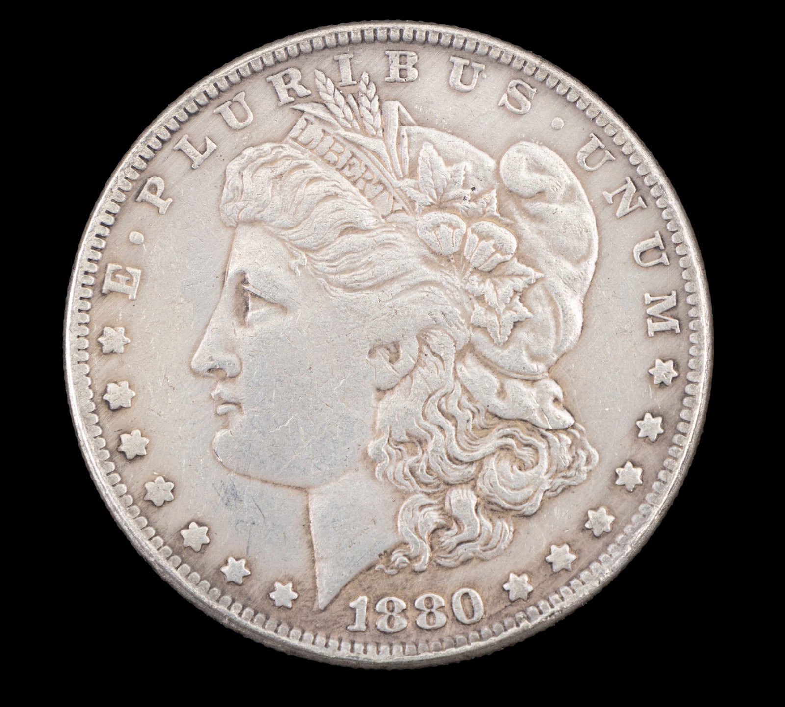 1880-CC Morgan Silver Dollar Coin: An 1880-CC Morgan Silver Dollar minted in Carson City. The obverse features Lady Liberty in profile, surrounded by stars and the inscription ?E Pluribus Unum.? The reverse displays a bald eagle with