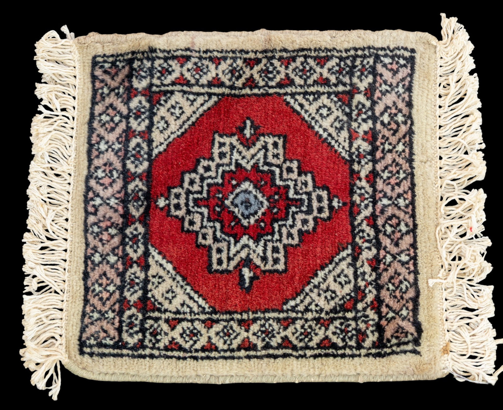 Pakastani Mini Rug: Pakastani mini rug with red and cream tones with a geometric design. Measures approx. 1' x 1'.