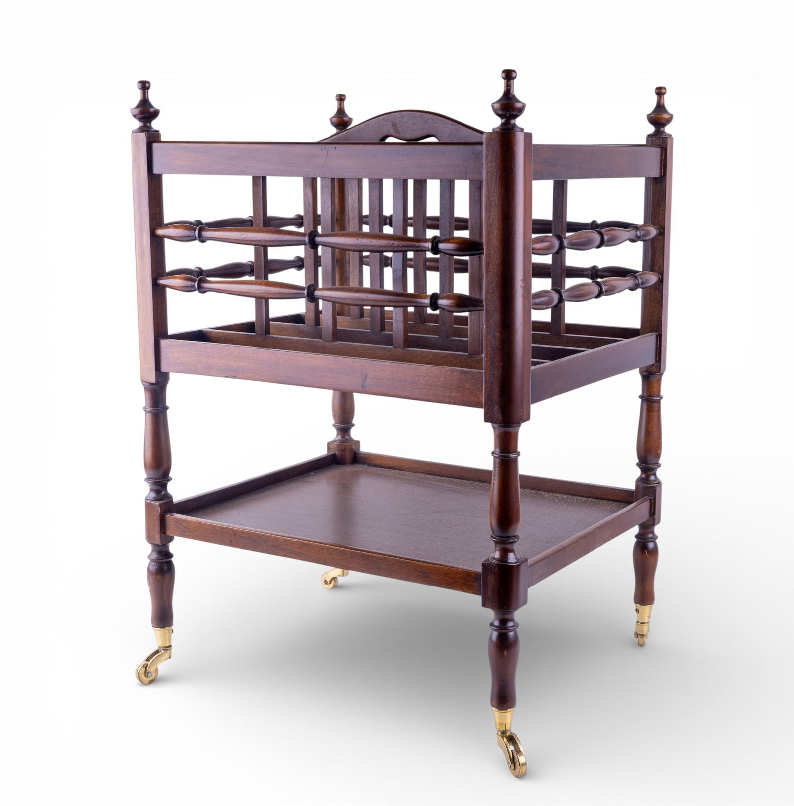 Mahogany Canterbury Magazine Rack: Vintage mahogany Canterbury-form magazine rack, featuring turned supports, slatted dividers, and a shaped carry handle at the top. Raised on turned legs terminating in brass castors. Measures approx.