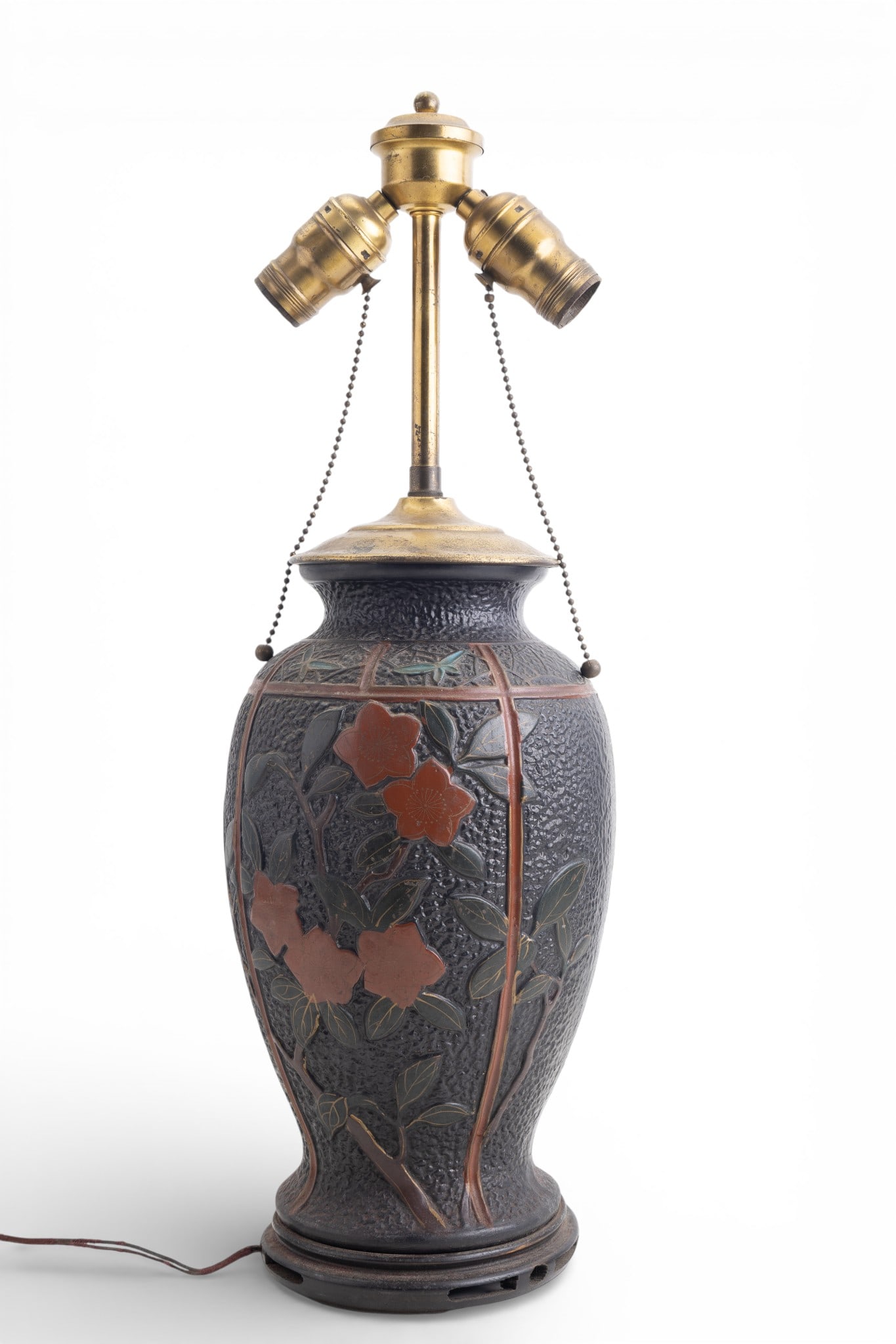 Early Japanese Double-Socket Lamp: Early Japanese table lamp featuring a textured body and raised floral panels framed by red banding. Fitted with a brass double-socket light cluster and pull chains. Marked "Japan" on the base. Measure