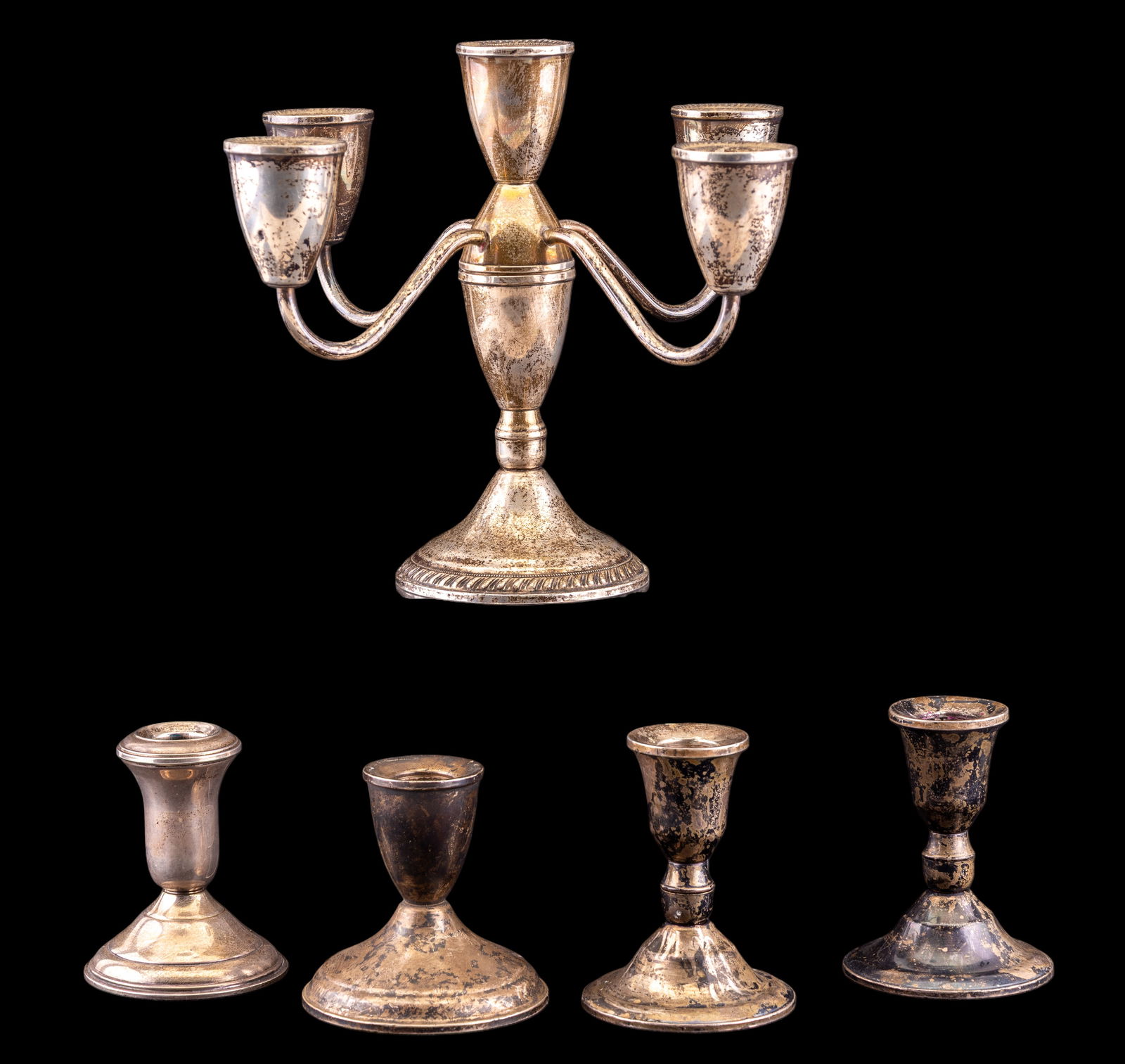 Weighted Sterling Candlesticks and Candelabra: A collection of four weighted sterling silver candlesticks, three of which are Duchin, one by AMC, each with an estimated approx. weight of 1.5ozt, and a 5-arm candelabra by Duchin, with an estimated