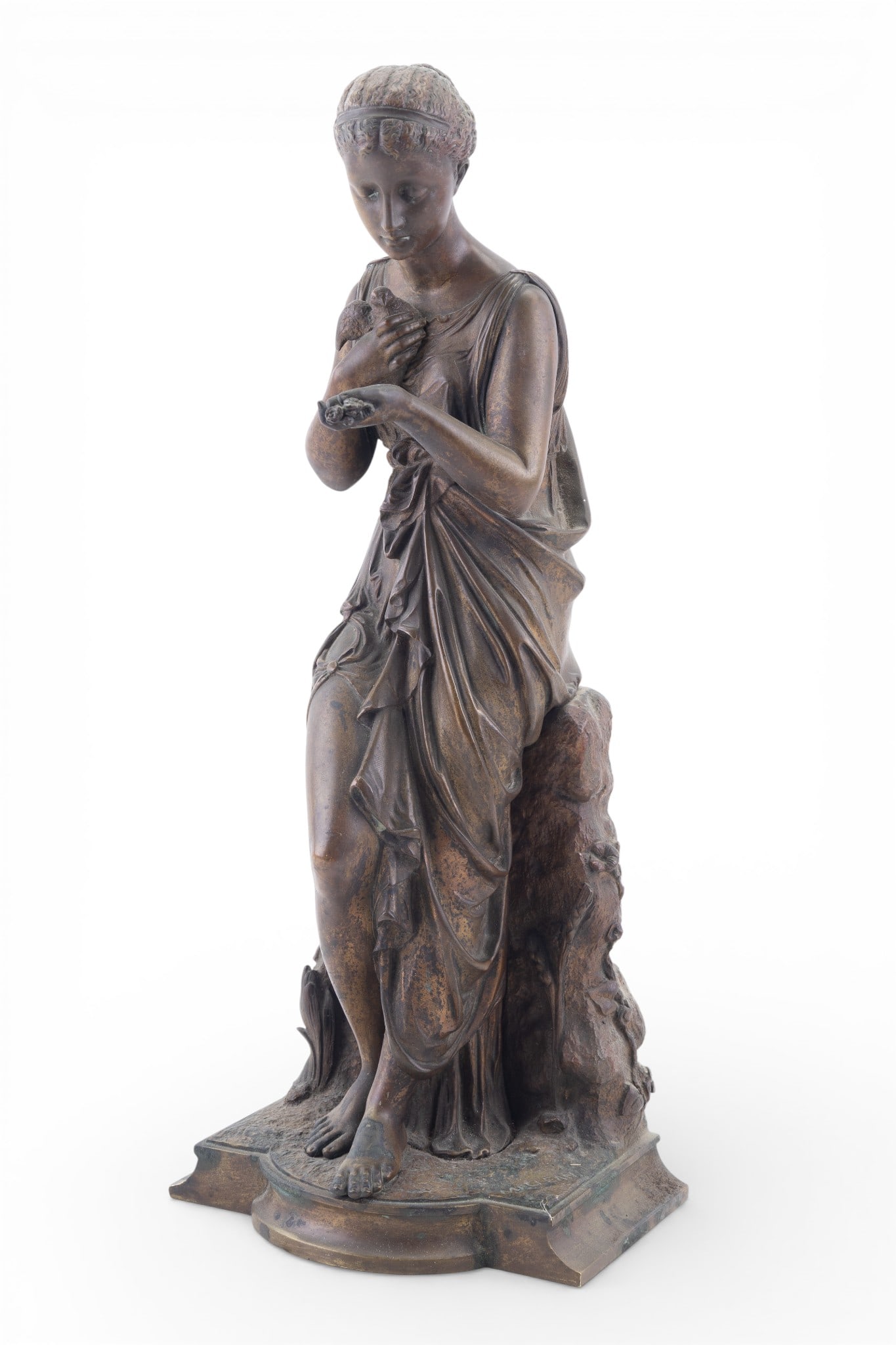 Bronze Figural Sculpture of a Woman, Maclean: Bronze figural sculpture depicting a draped classical woman in contrapposto pose, holding flowers and a dove, leaning against a naturalistic wall. Signed "MACLEAN" on base. Measures approx. 15" H.