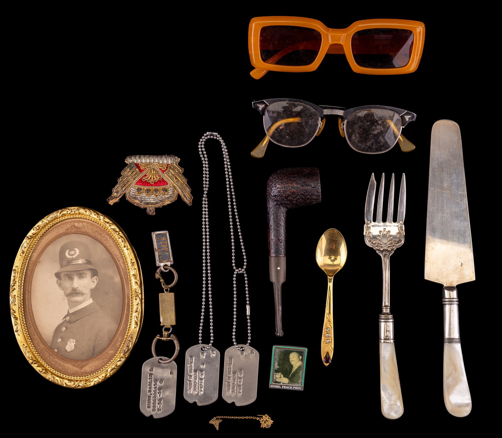 Sterling Utensils, Vintage Eyeglasses, and More: A collection of various items including sterling silver and mother of pearl cake knife and serving fork, vintage Wimbledon tobacco pipe, vintage United States Military dog tags, a Viners of Sheffield