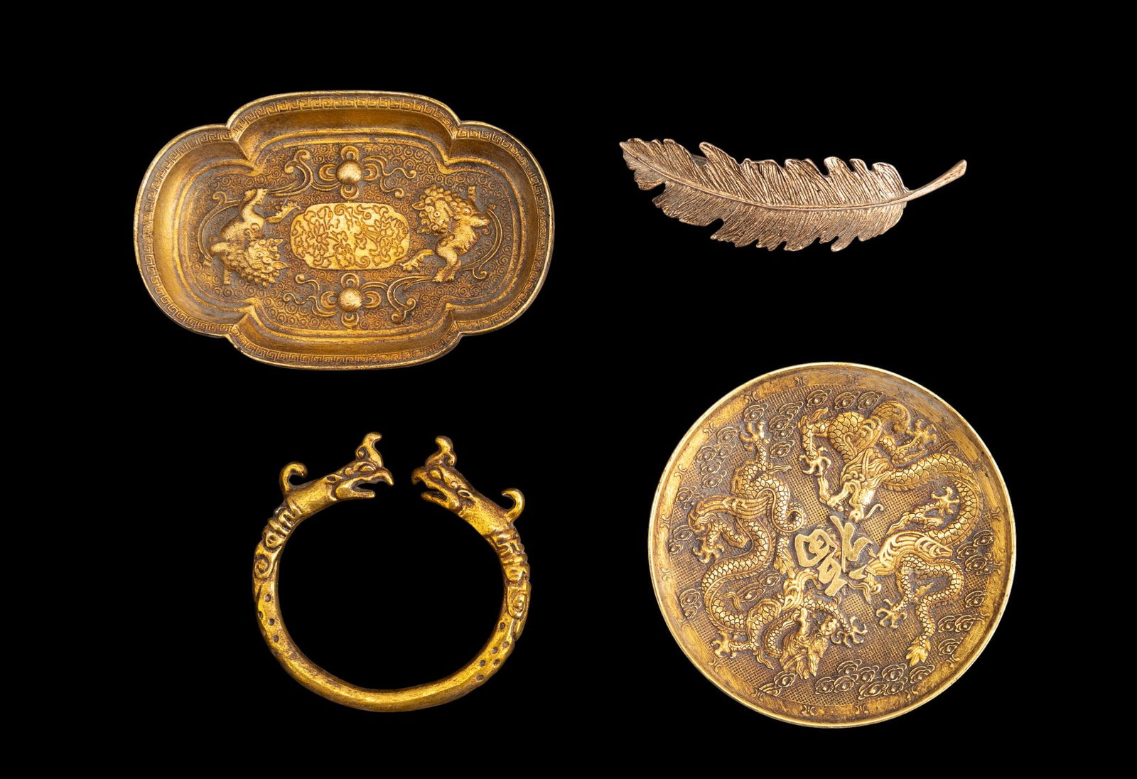 Chinese Gold Tone Jewelry and Accessories: A gold tone feather barrette, a gold tone figural cuff bracelet, and two gold tone vanity dishes, depicting dragons and foo dogs.
