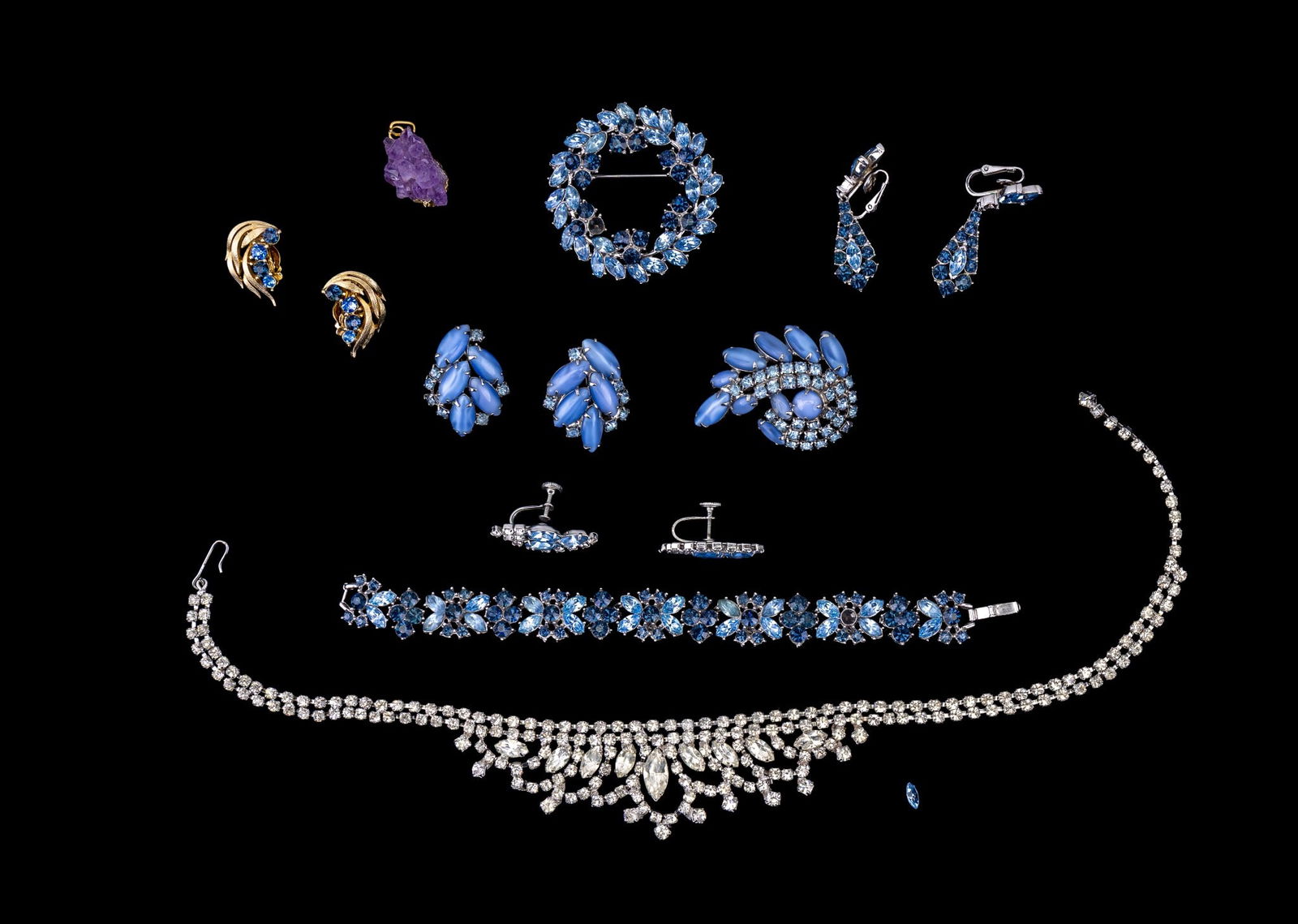 Trifari, Lisner, and Vintage Rhinestone Jewelry: A two tone blue rhinestone and silver tone set by Trifari including a tennis bracelet, note one rhinestone will require replacement, clip on drop earrings, a wreath shaped brooch, a pair of gold tone