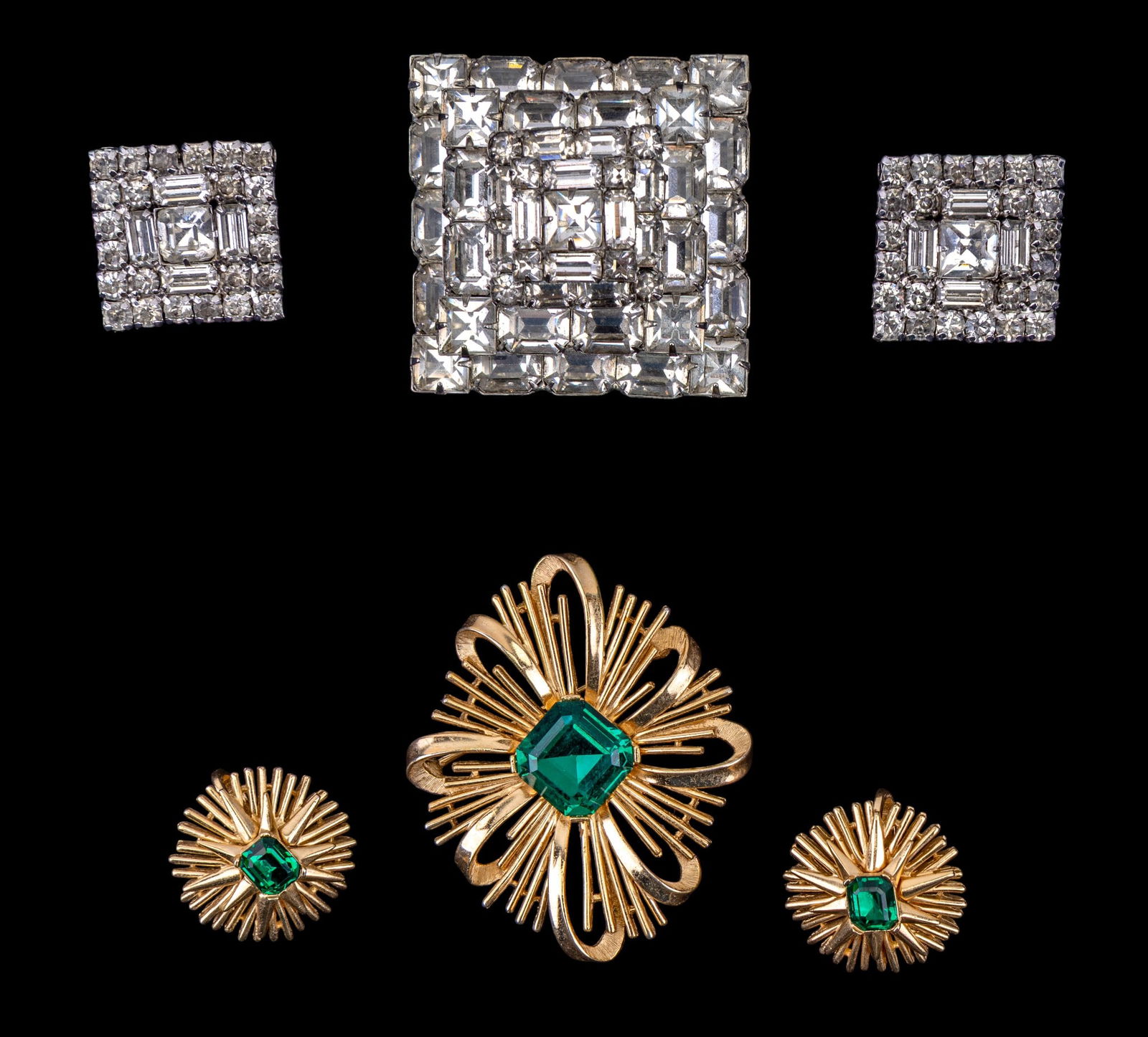 Weiss and Trifari Vintage Jewelry Sets: A silver tone and white rhinestone geometric brooch with matching clip on earrings by Weiss and a green rhinestone and gold tone sun burst brooch with matching clip on earrings by Trifari.