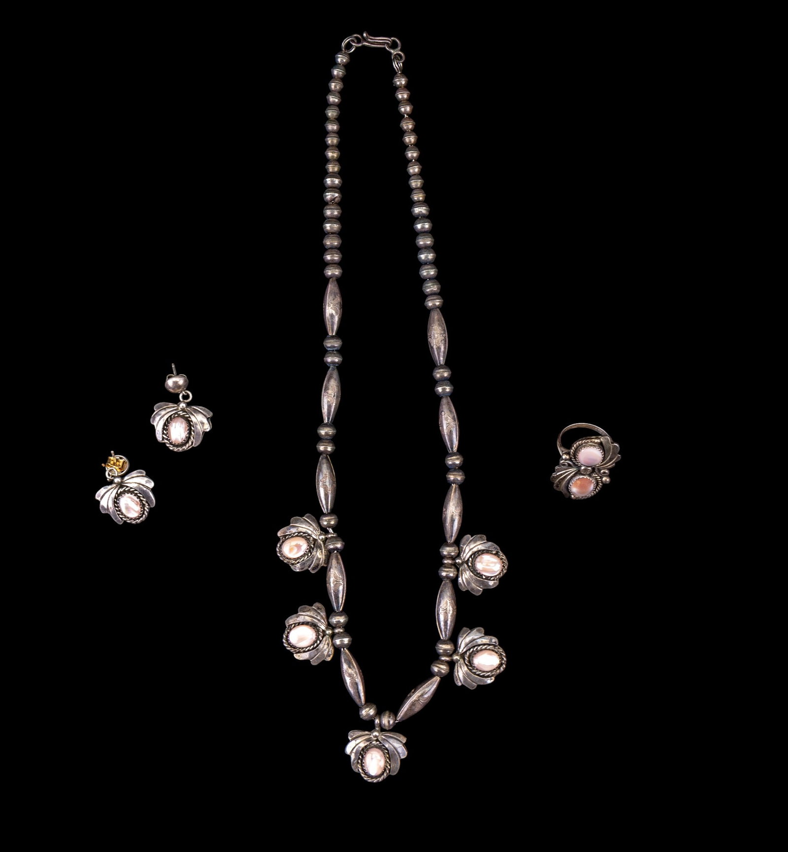 Native American 925 & Pink Mother Of Pearl Jewelry: A collection of artisan made Native American sterling silver jewelry featuring pink mother of pearl cabochons including a necklace and stud earring set signed 'B. J. B.' and a ring signed 'VM'. Ring s