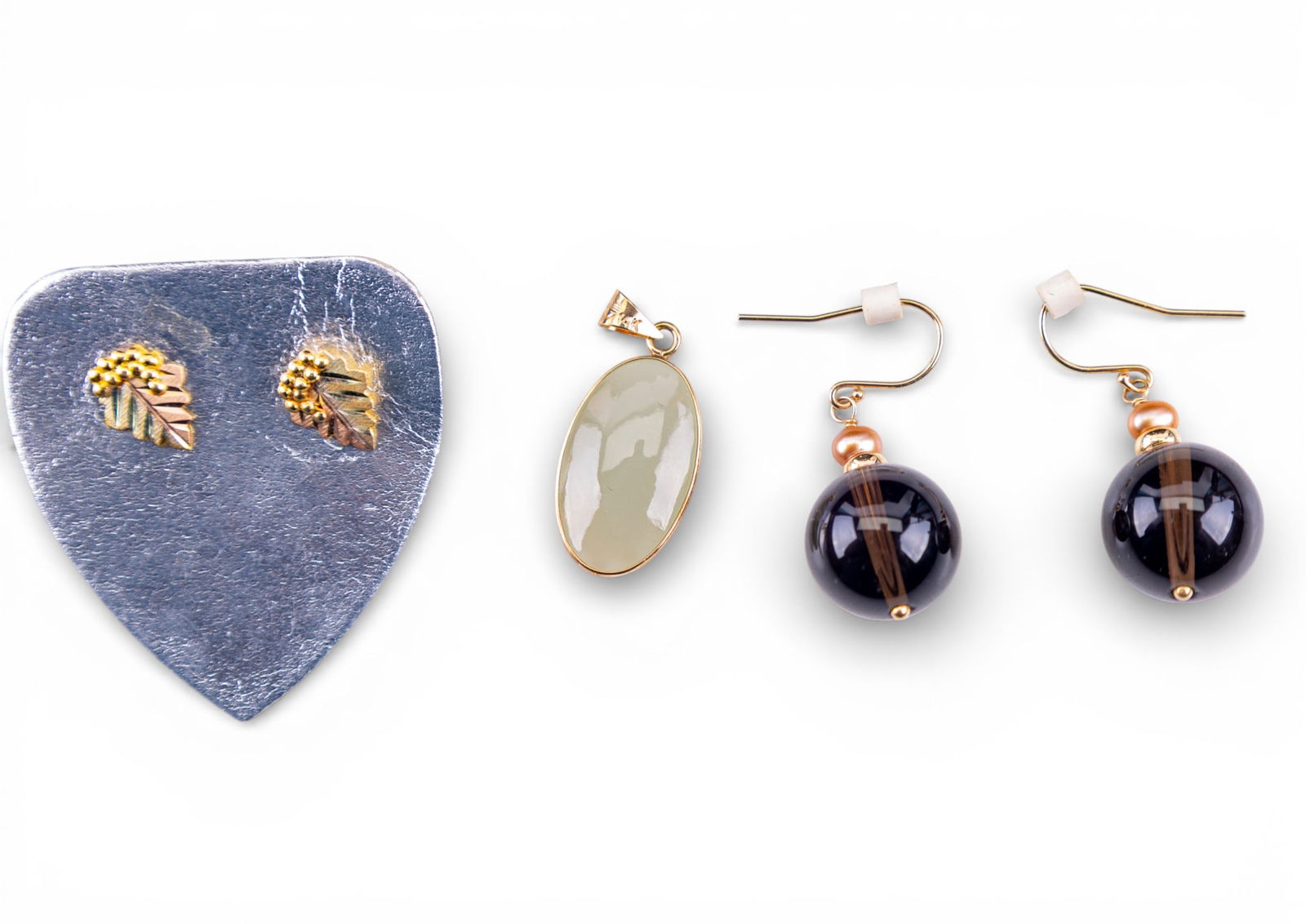 14K Gold and Stone Jewelry: An oval jade pendant featuring a 14K gold etched floral frame and bail, a pair of smoky quartz spherical French hook earrings with 14K gold hooks, and a pair of 10K gold grape and leaf stud earrings w