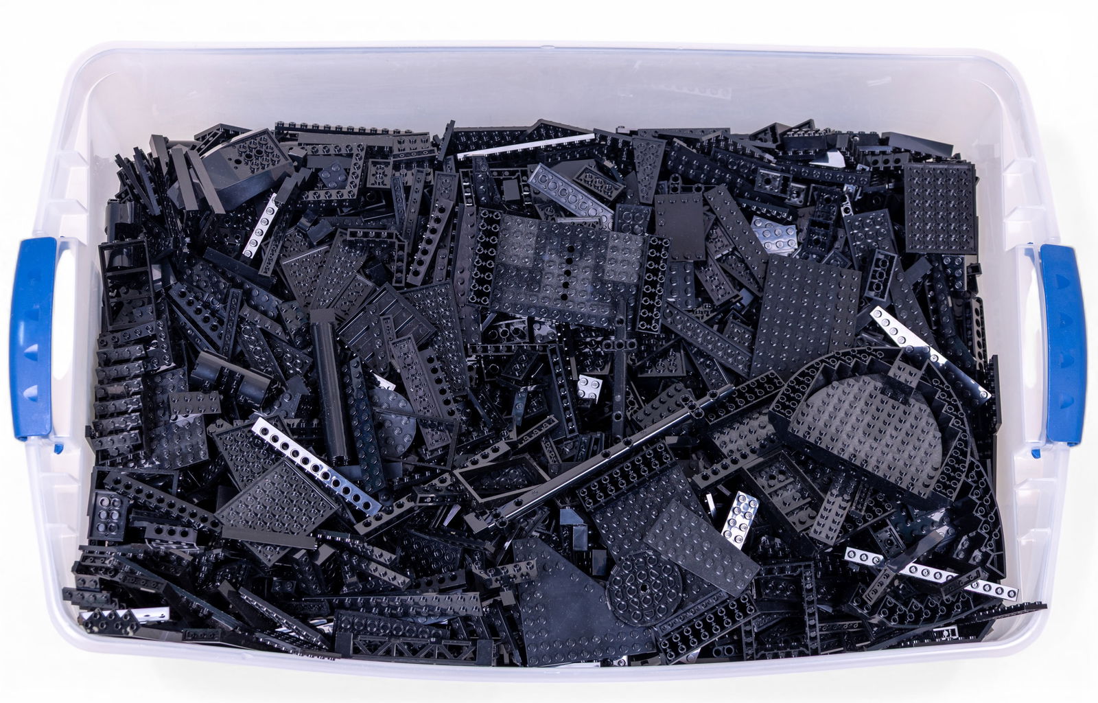 33 Pounds of Black Lego Pieces: Approximately 33 pounds of black Lego pieces in a variety of shapes and sizes. Pieces include plates, bricks, connectors, and other standard Lego elements. Stored in a rectangular plastic container.