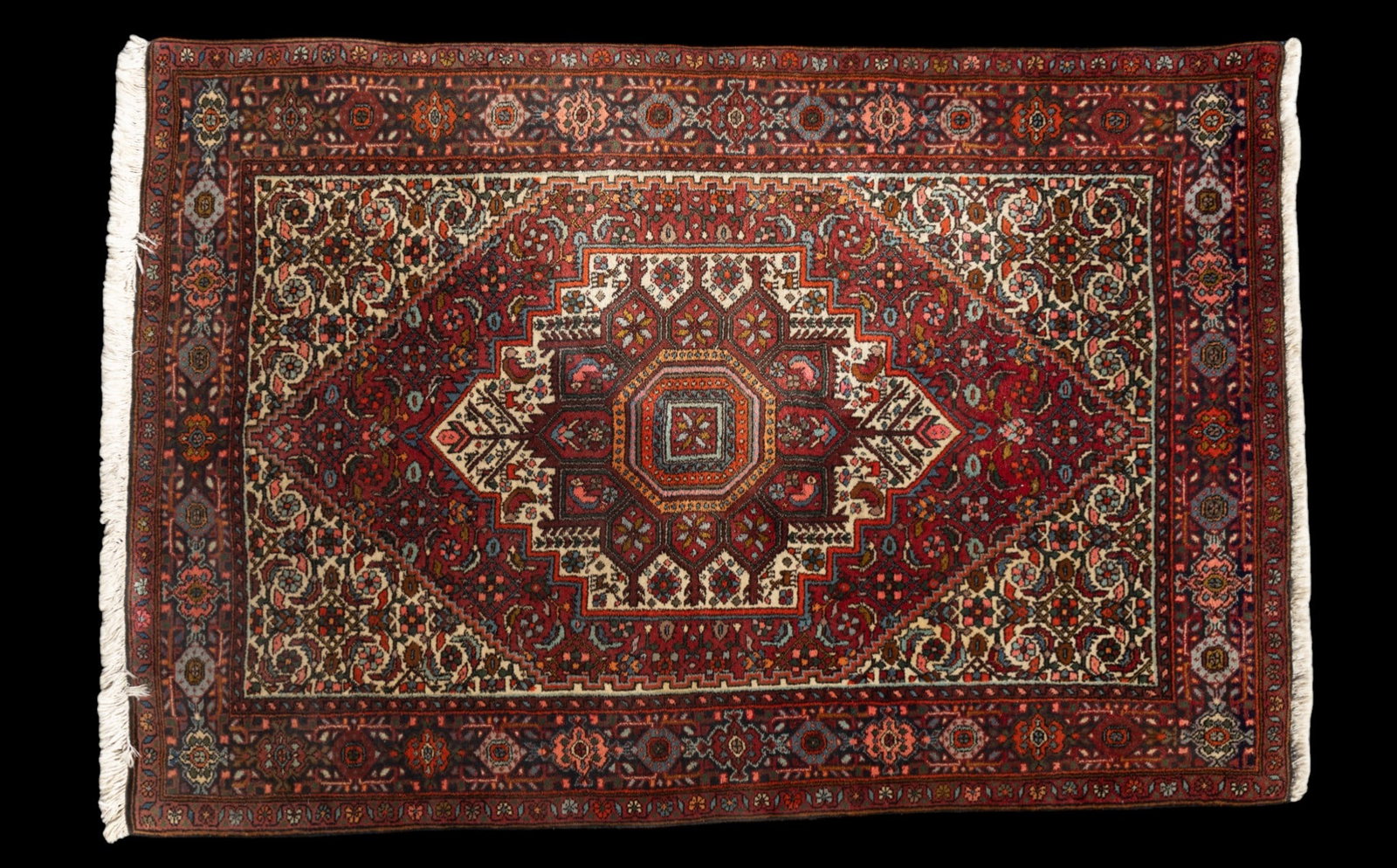 Persian Rug Central Medallions: Persian area rug with geometric motifs against a deep red ground with beige highlights and scrolling motifs. Measures approx. 5'1" x 3'6".
