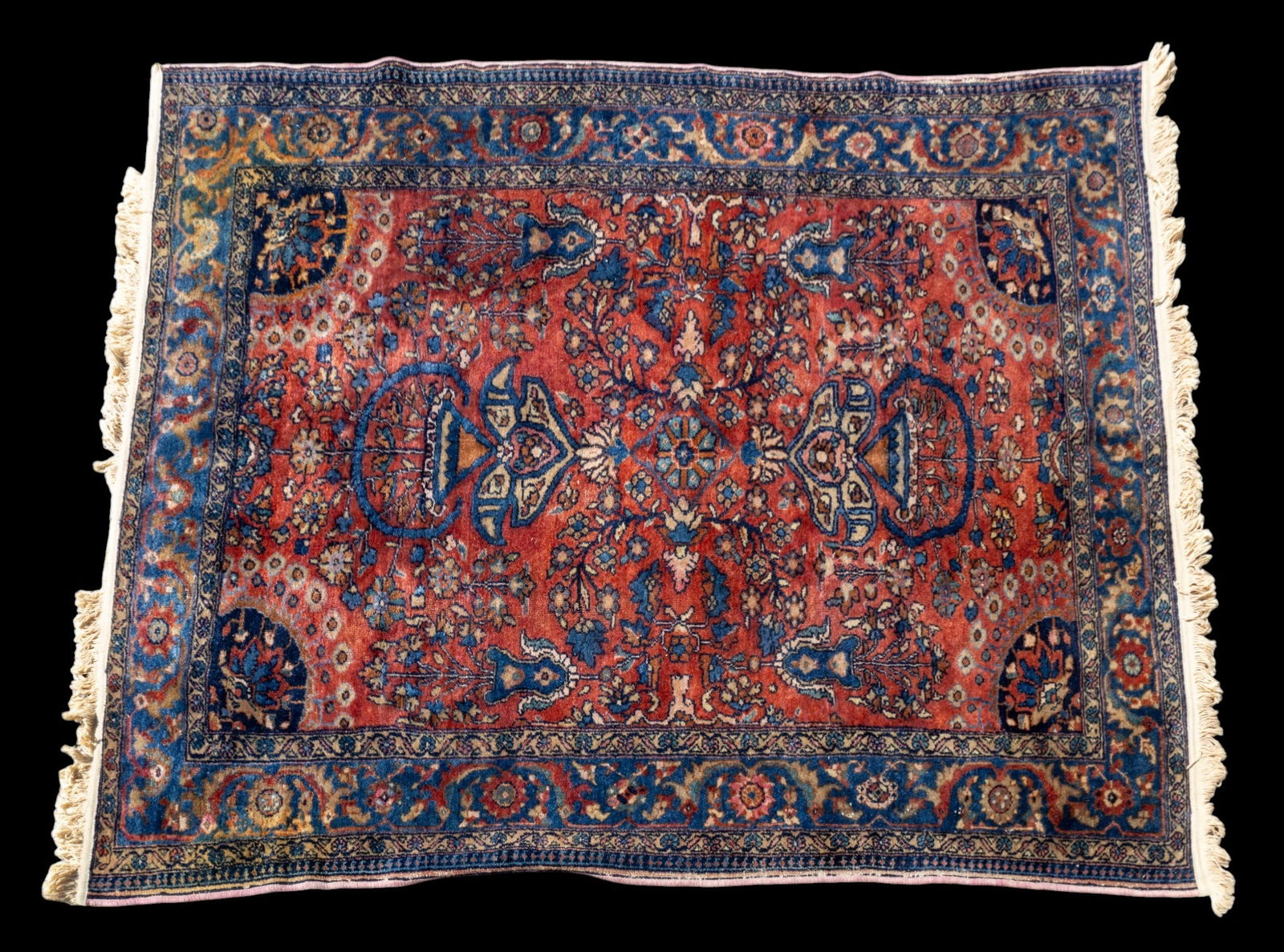 Hand Woven Wool Persian Sarouk Rug: A hand woven wool Persian Sarouk rug featuring a multicolored floral motif on a brick red background, note some loss to pile, edge, and fringe. Measures approx. 5' 2" W x 6' 3" L.