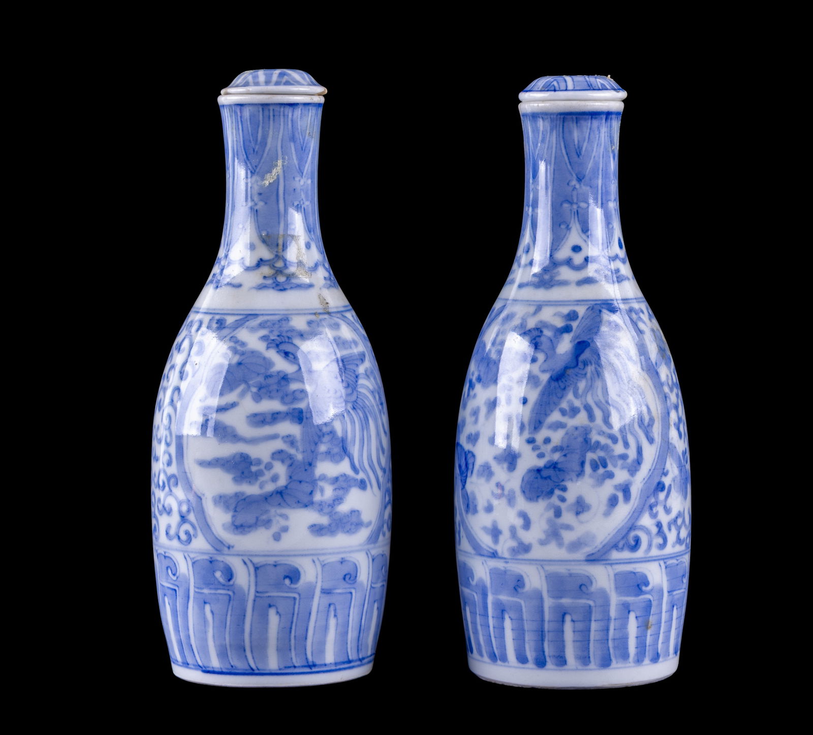 Pair of Japanese Blue & White Sake Bottles: Pair of Japanese blue and white porcelain sake bottles, each of slender form with flared neck and fitted porcelain lids. Decorated in underglaze blue with motifs including birds and foliage. Each meas