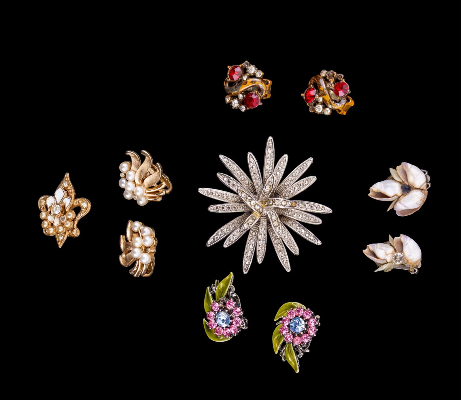 Trifari and Other Costume Jewelry: A pair of Trifari gold tone and faux pearl clip on earrings, vintage rhinestone and enamel clip on earrings, a vintage pot metal brooch, a gold tone Fleur de Lis brooch, and seashell clip on