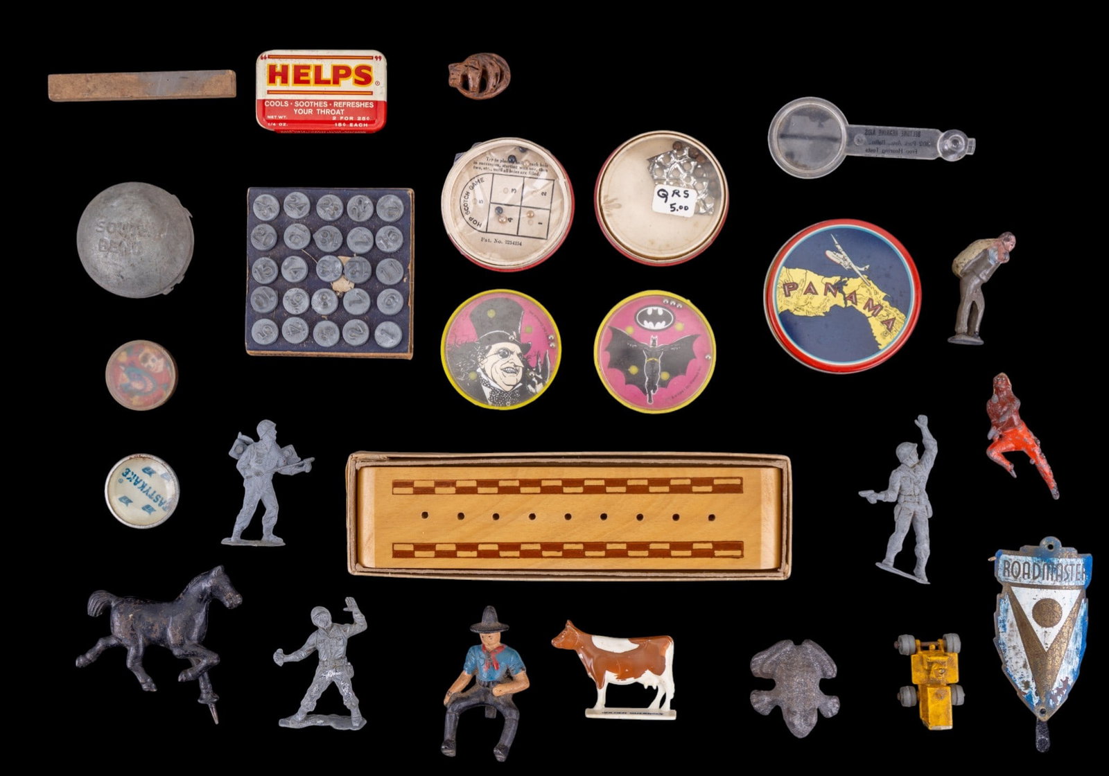 Early Iron and Tin Figurines and More: A collection of early iron and tin figurine toys, a small cribbage board game, a Roadmaster bicycle head badge, Acro numbering tacks, and more.