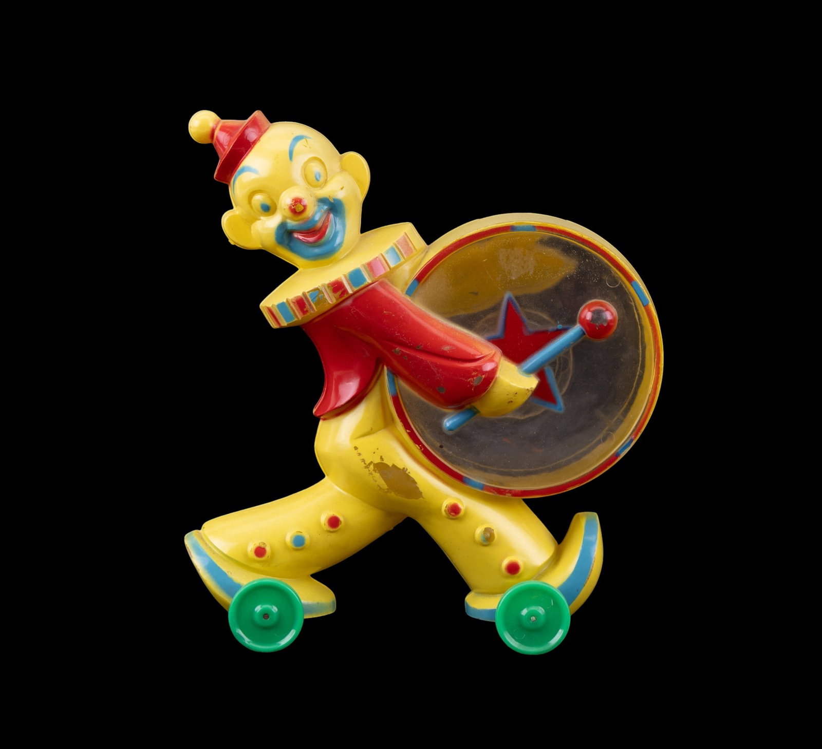 Vintage Rosbro Rosen Clown Bank: Hard plastic clown bank manufactured by Rosbro Rosen, likely from the 1950s. Features a colorful clown figure on wheels, holding a drum with a red star design. The figure includes vibrant yellow, red,