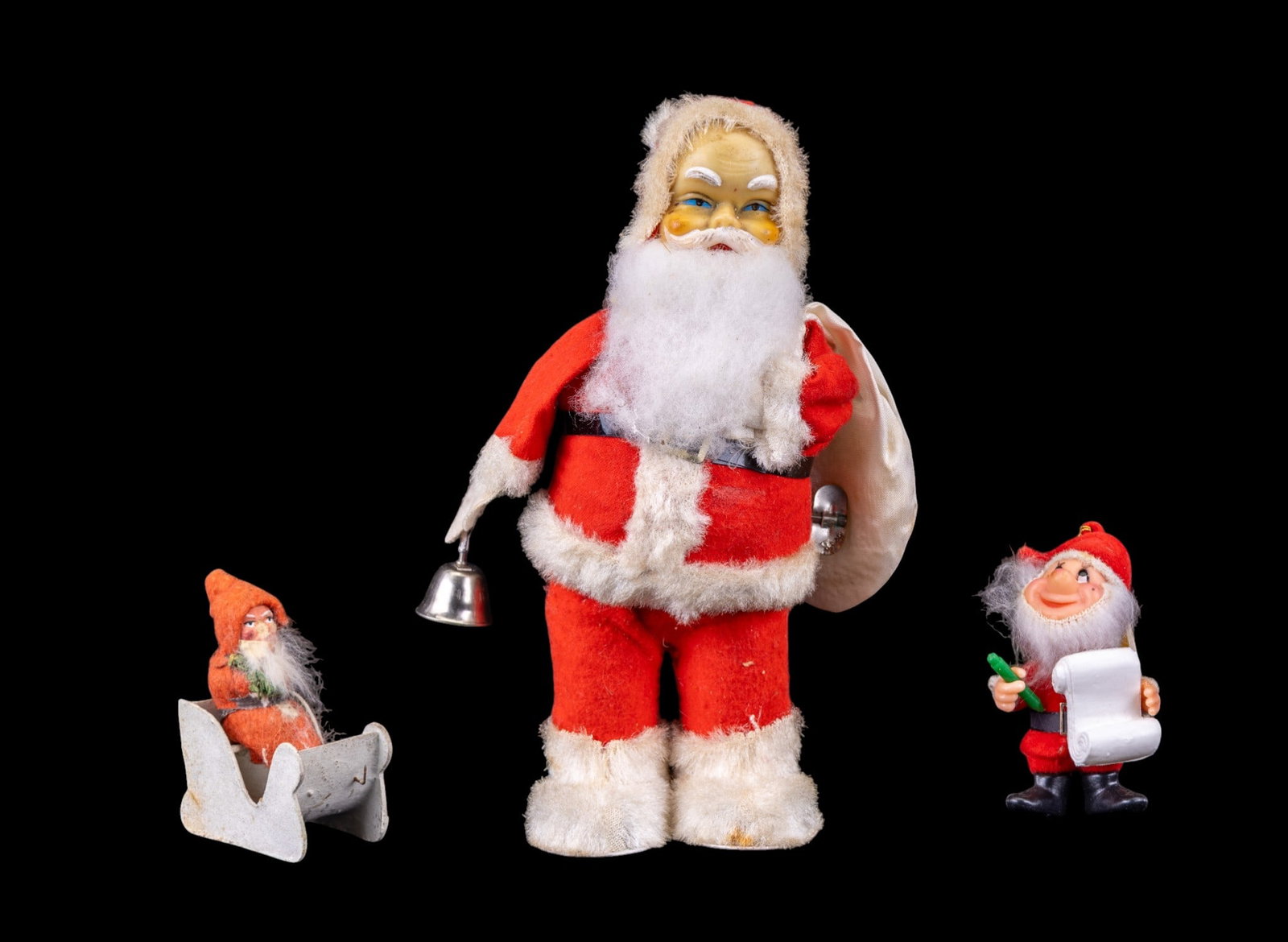 Antique German Santa, Gnome, Sleigh Ornaments: Three Christmas-themed items including a wind-up Santa Claus figurine with a bell, approximately 6 inches in height, a gnome Christmas tree ornament holding a scroll, and an antique clay Santa seated