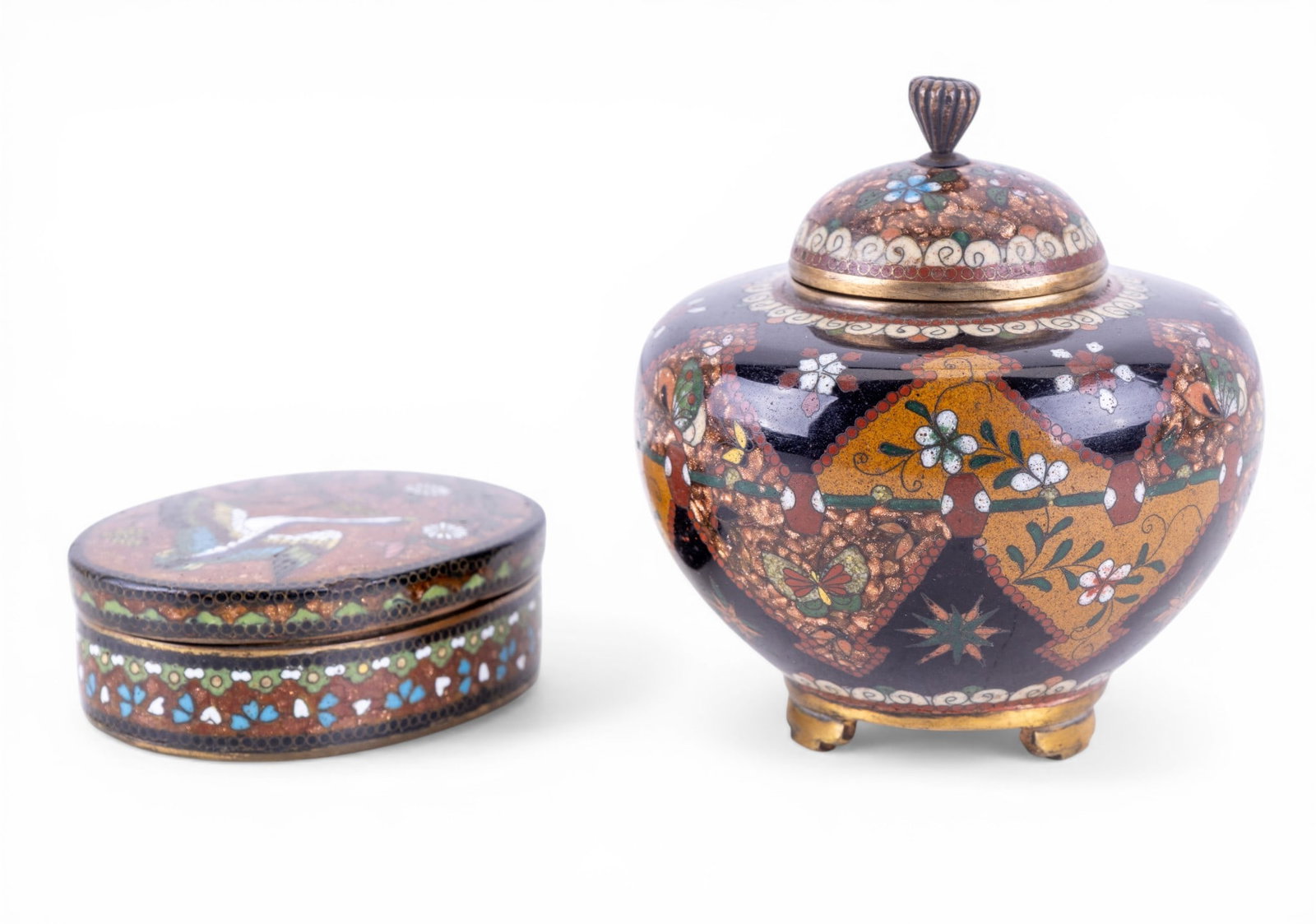 Japanese Cloisonne Enamel Lidded Vessels: Companion pair of Japanese cloisonne enamel lidded vessels, including a covered jar and a matching rounded box. Each example features dense floral and geometric decoration in multicolored enamels on