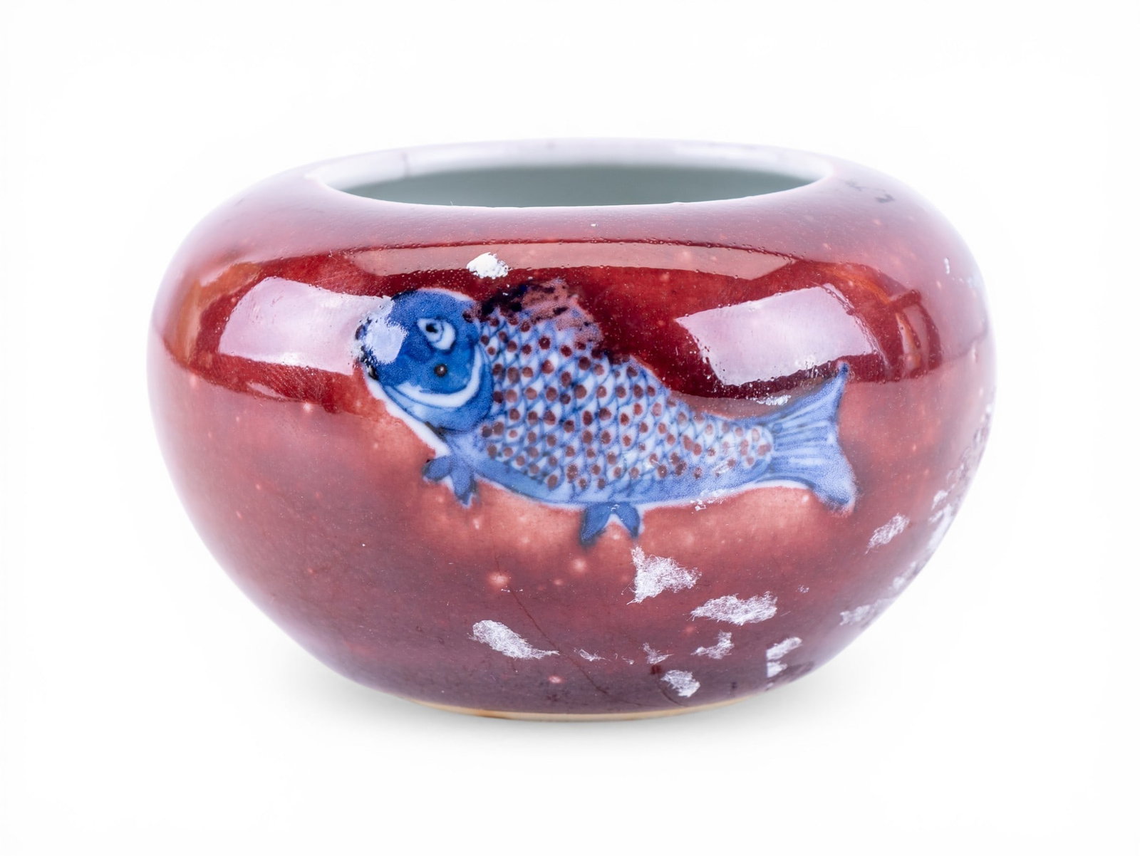 Small Chinese Fish Vase: Small Chinese porcelain vessel of rounded form, dark red glaze and reserves featuring blue fish motifs. Base bears a 4-character blue mark. Measures approx. 3" Diameter.