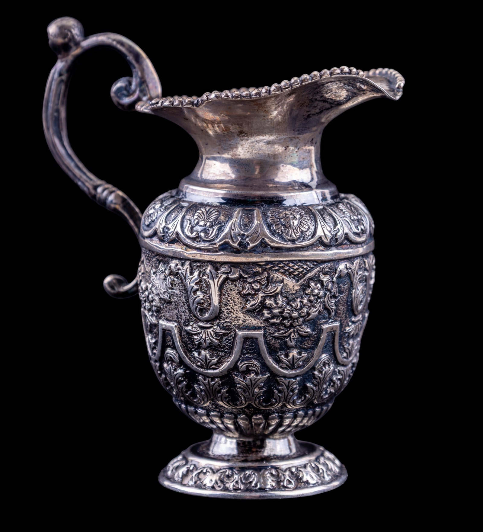French Silver Figural Creamer: French silver creamer of baluster form, richly decorated with repousse and chased foliate and scrollwork motifs throughout the body. Measures approx. 4.5" Tall.