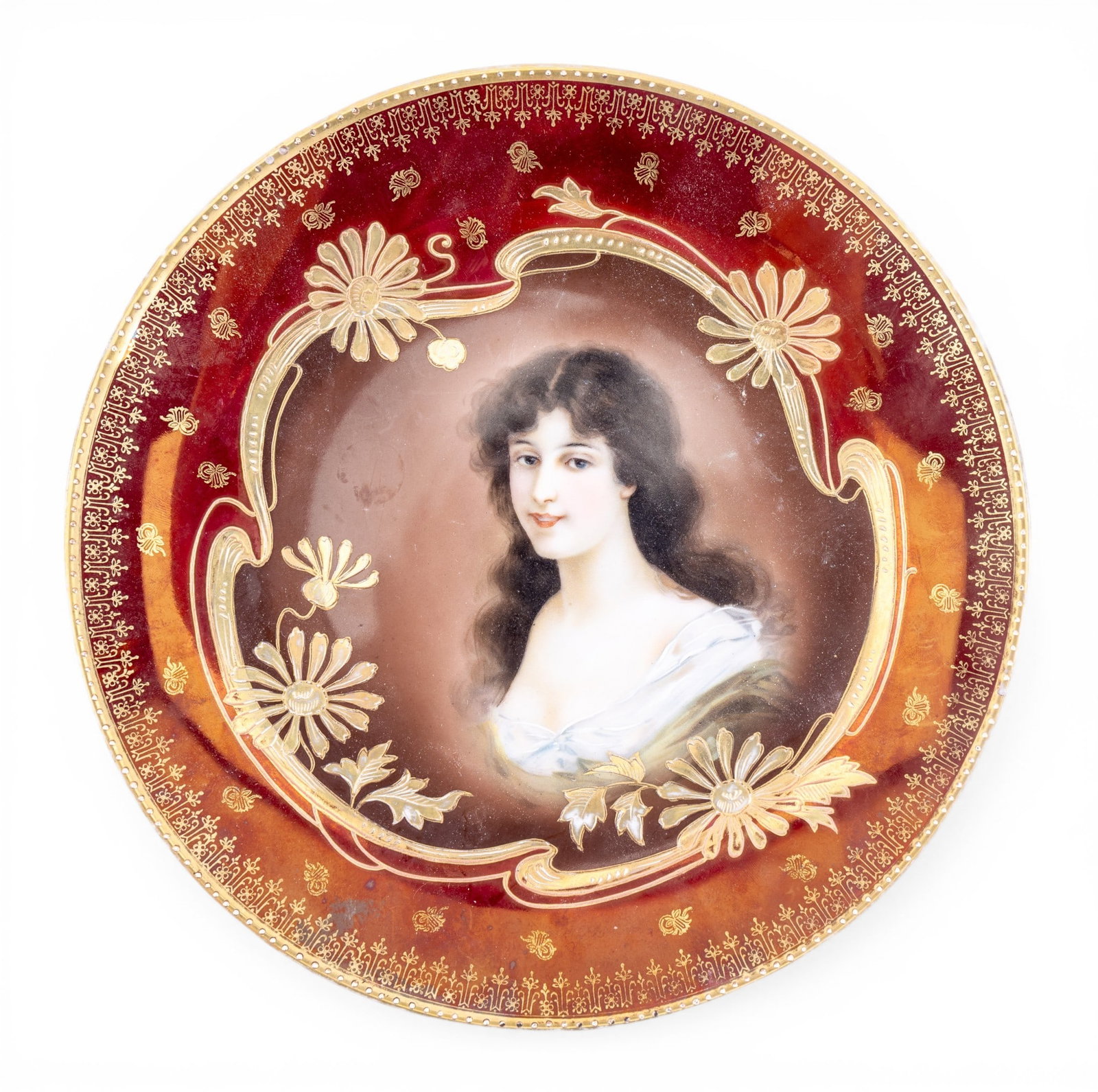 Antique Royal Vienna Hand Painted Porcelain Plate: An antique porcelain plate produced by Royal Vienna featuring a three quarter portrait of a young woman with dark hair, featuring a burgundy colored border with gold accents, marked on the reverse,