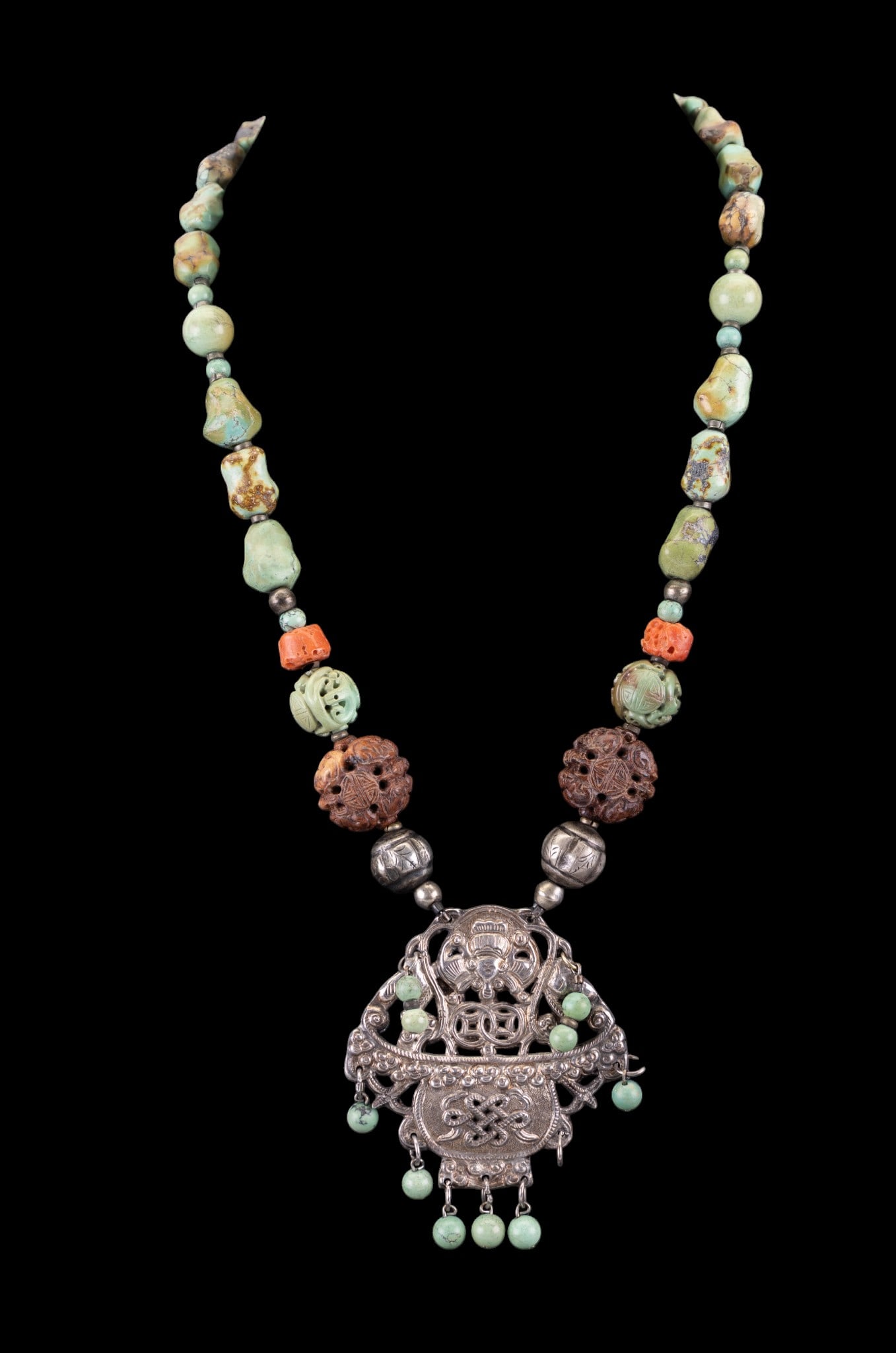 Chinese Turquoise Necklace: A Chinese necklace featuring natural turquoise, carved coral and wood beads and Chinese silver tone pendant, approx. 10.5" on the drop.