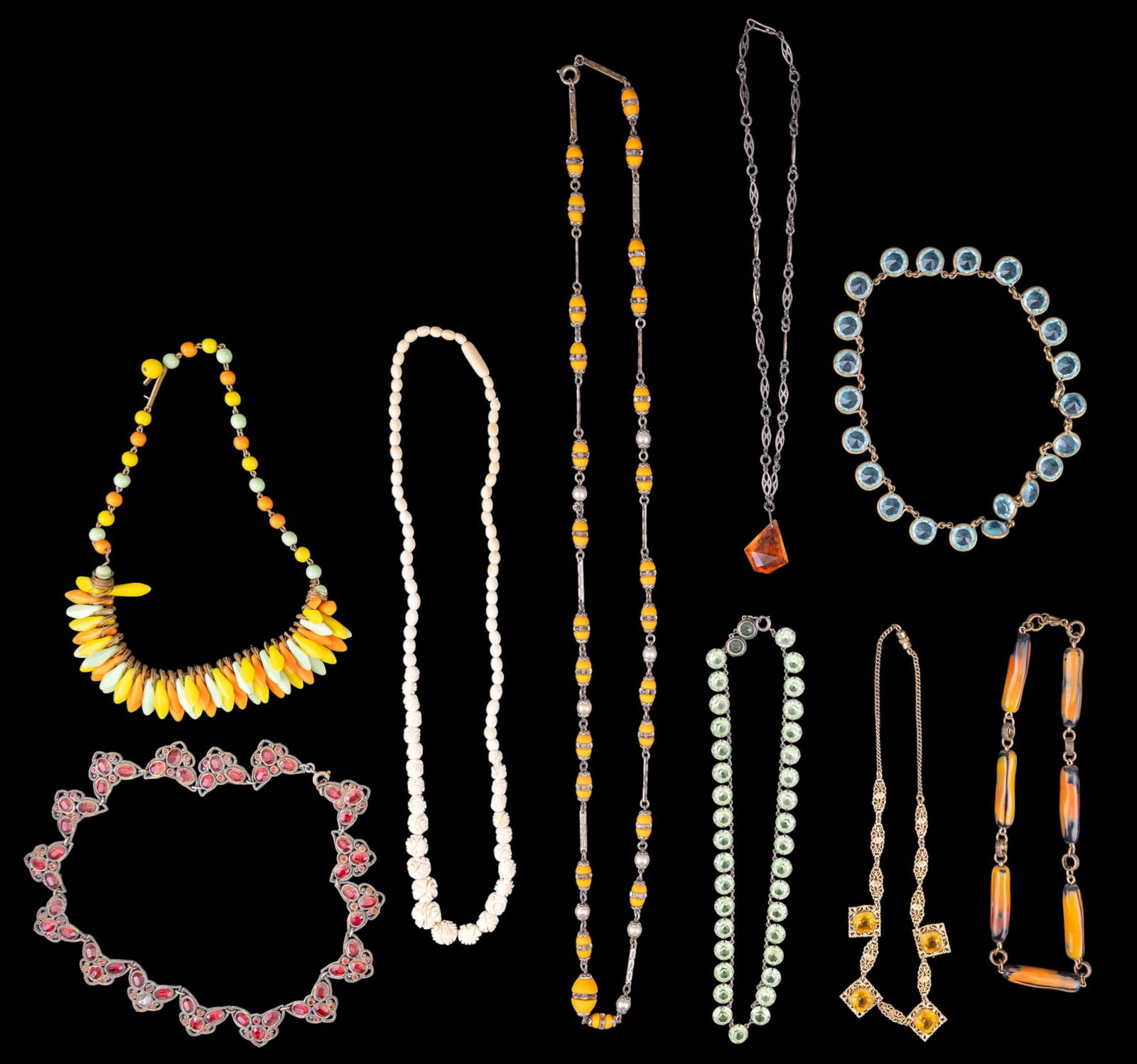 Art Deco Jewelry Collection: Variety of early vintage art deco necklaces including a sterling and light green glass necklace, orange glass necklace, carved floral necklace and orange and green hued necklace.