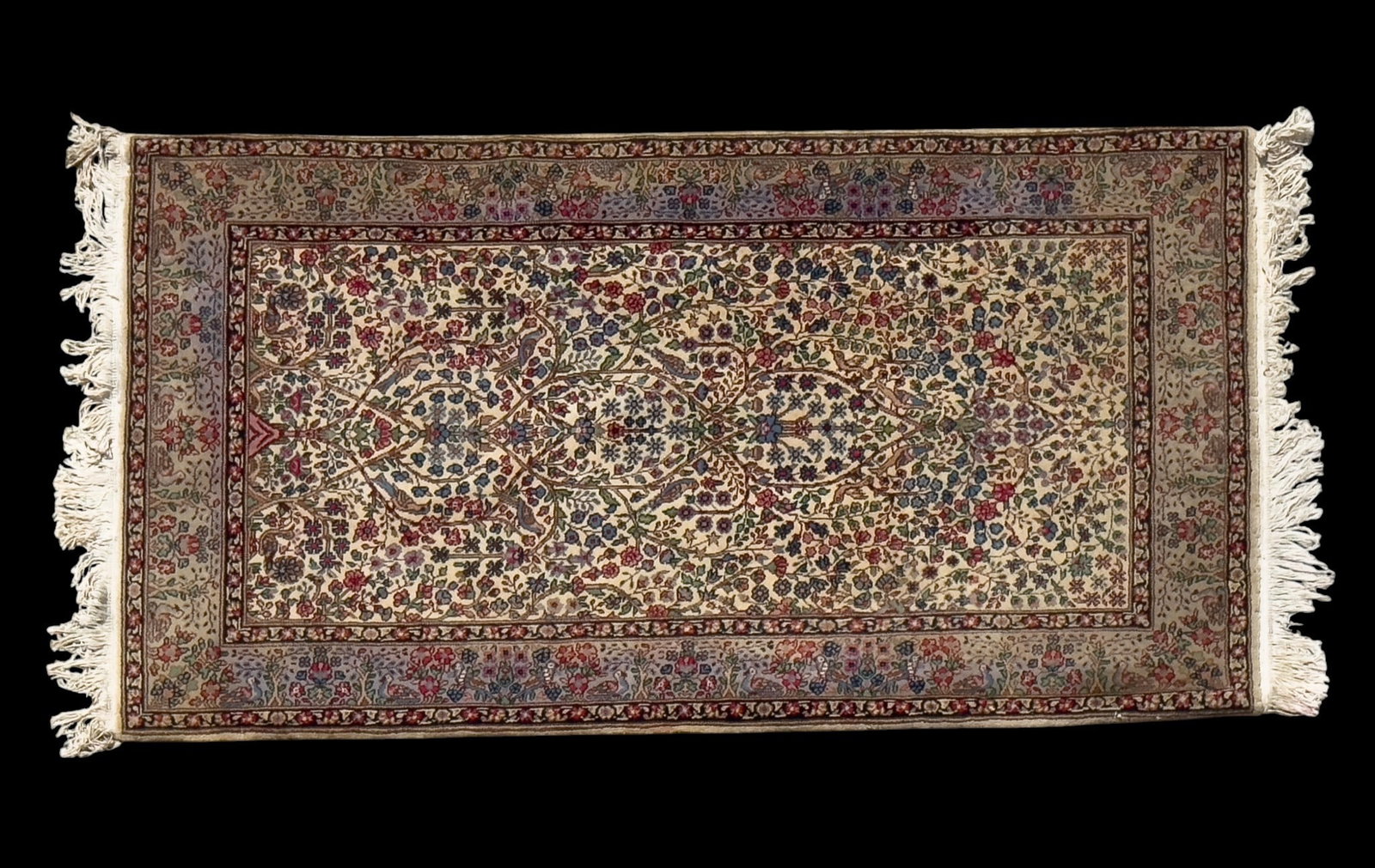 Persian Kirman Rug: Persian Kirman area rug with a cream central ground surrounded by a dark border with floral motifs. Measures approx. 3' x 5'2".