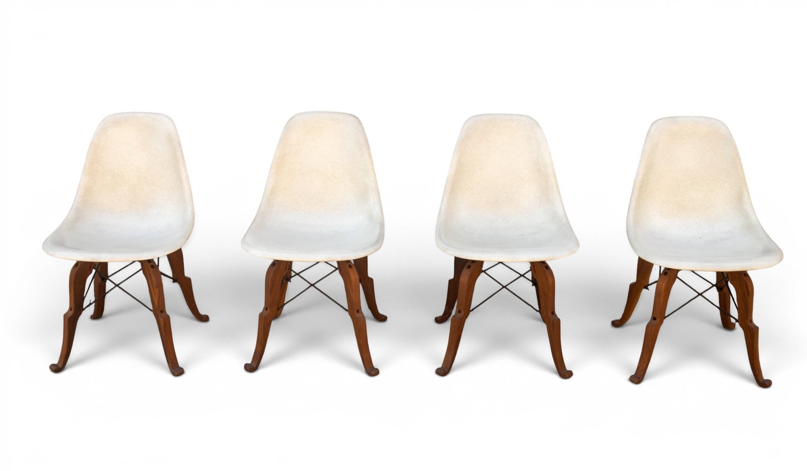 White Eames-Style Shell Chairs (4): Four fiberglass shell chairs with a mid-century modern Eames-style shell chair design with Eiffel style stretcher. The molded fiberglass seats feature a textured surface in a pale hue, supported by co