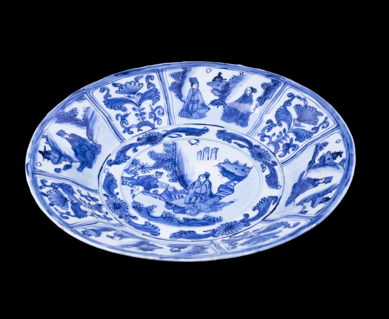 Chinese Blue and White Figural Charger: Chinese blue and white porcelain charger, decorated with central figural courtyard scene surrounded by radiating panels of scholars and floral motifs. The cavetto and rim feature alternating figural a