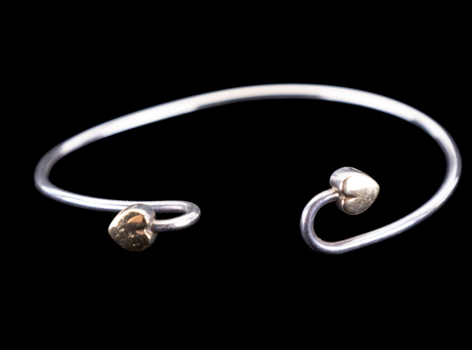 Tiffany and Co. Sterling and 18K Gold Bracelet: Delicate sterling silver cuff bracelet signed Tiffany and Company, made of sterling silver with 750/18k gold heart shaped ends.