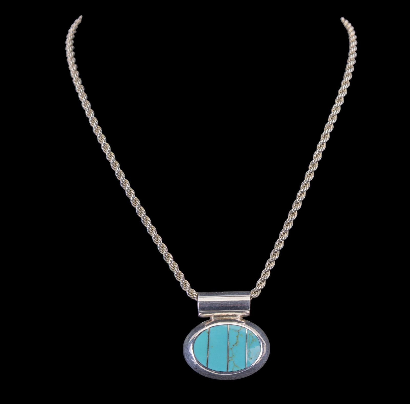 Turquoise and Sterling Necklace: Sterling silver rope chain with large oval inlaid turquoise pendant.