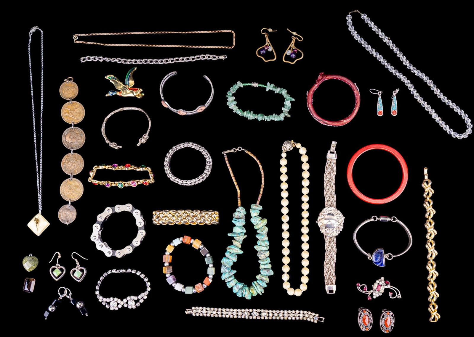 Bakelite, Trifari, and Other Costume Jewelry: A collection of costume jewelry including an English coin bracelet, Trifari gold tone bow panel bracelet, facet cut crystal necklace with sterling silver clasp, chunky green hardstone bracelet, red Ba