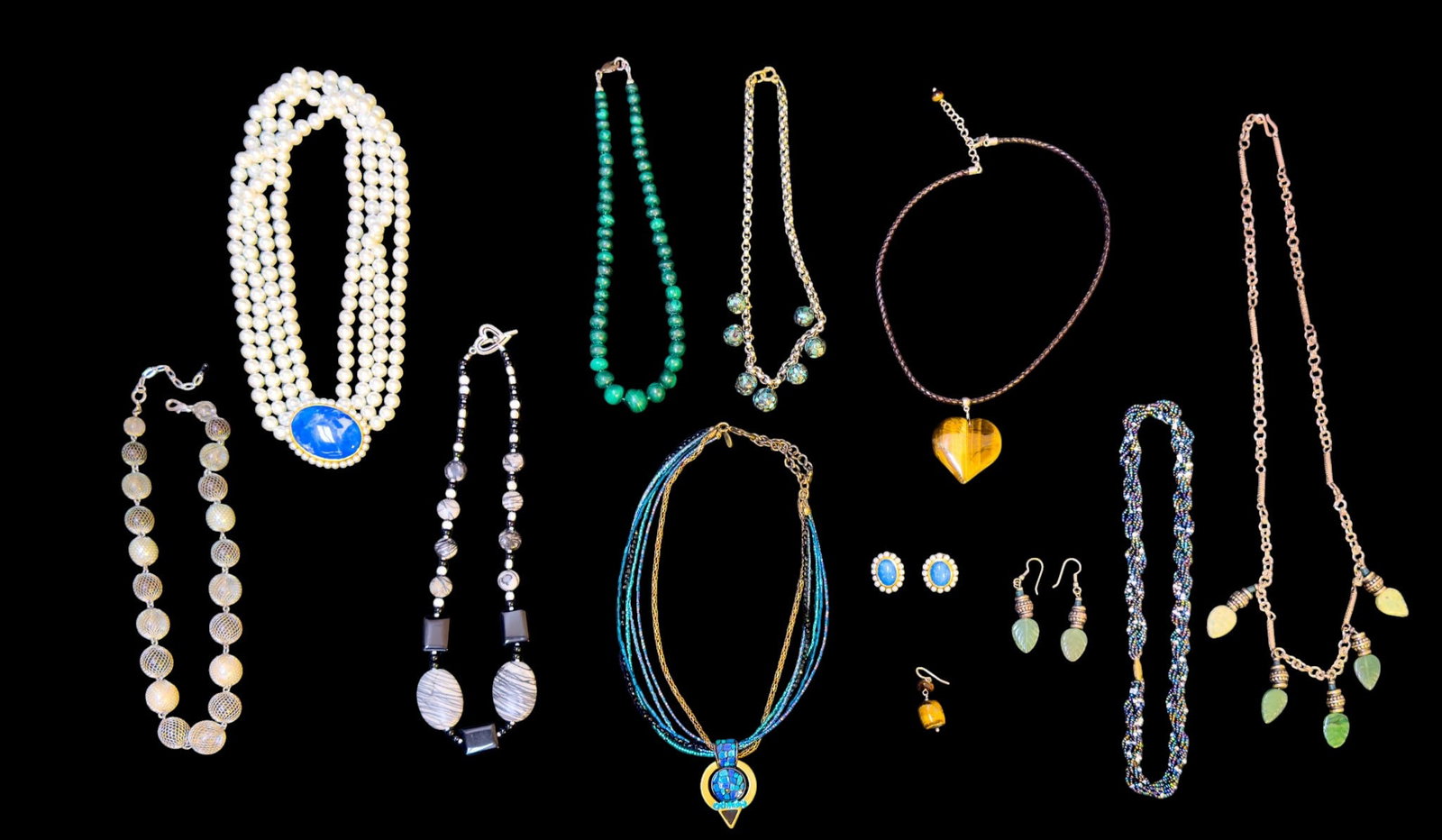 Natural Stone and Other Necklaces: A collection of necklaces featuring a graduated spider jasper and glass necklace, a graduated malachite bead necklace, a heart shaped tiger's eye pendant on a braided leather cord, a leaf motif jade c