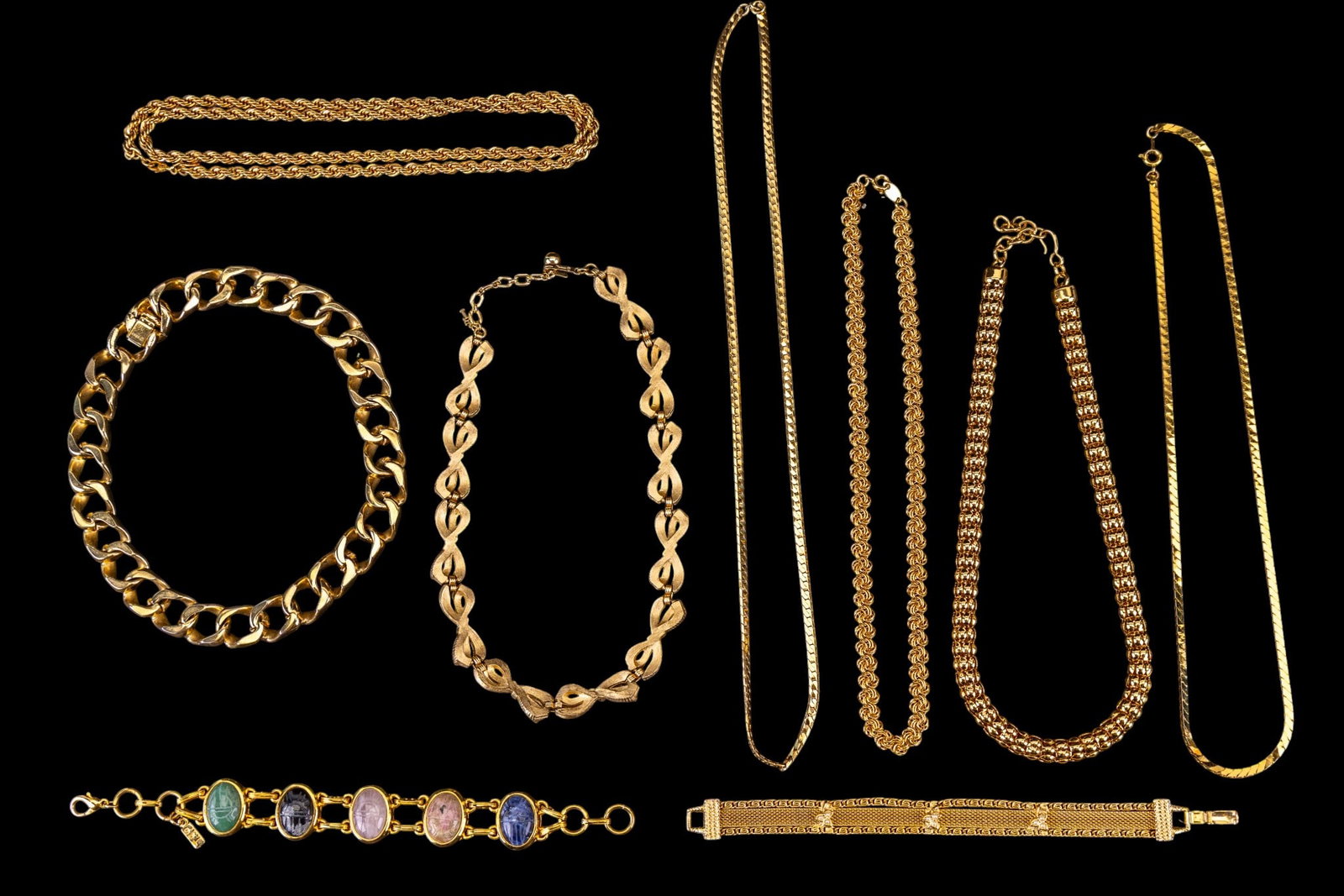 Designer Gold Tone Jewelry: A collection of designer gold tone necklaces including brands such as Monet, Trifari, Goldette, Ciner, a scarab bracelet marked 'T.S.', and more.