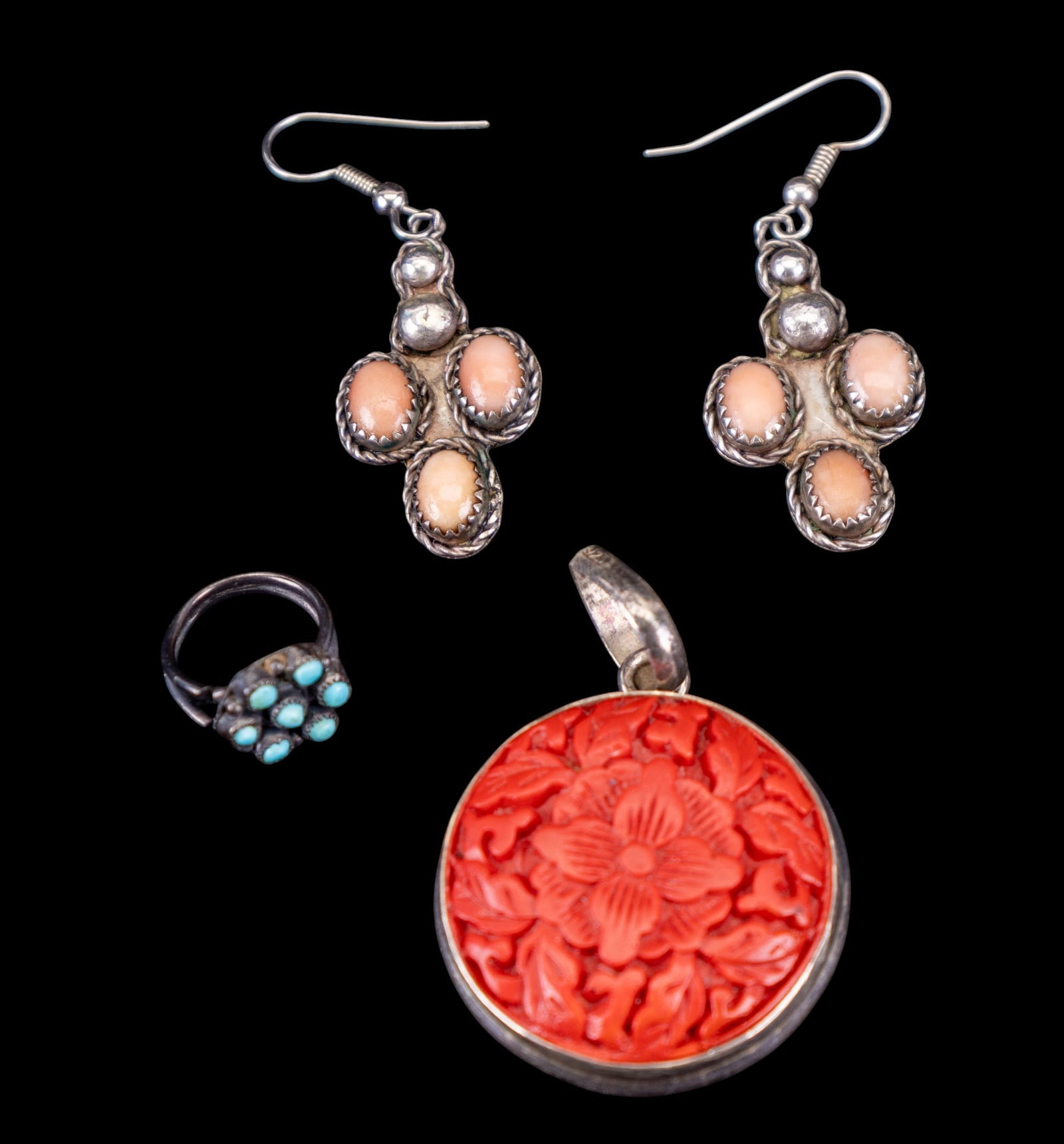 Coral, Cinnabar, & Turquoise Jewelry Group: A small artisan turquoise cabochon ring, not marked, size 2, a carved cinnabar floral pendant, bale marked '925', and a pair of pink coral cabochon French hook earrings.