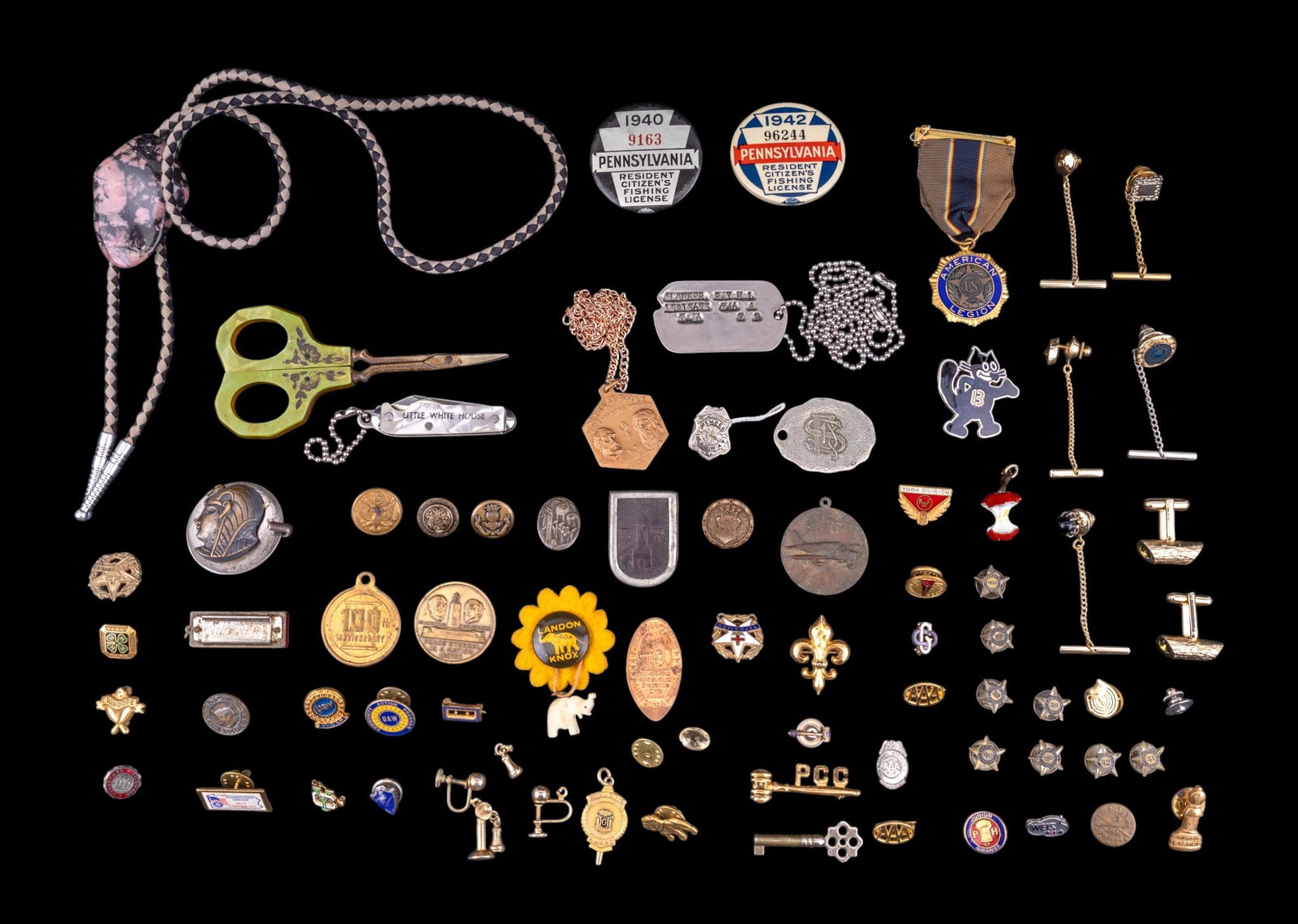 Buttons, Pins, and More: A collection of buttons, pin backs, lapel pins, cufflinks, charms, dog tags, natural stone and leather bolo tie, and more.