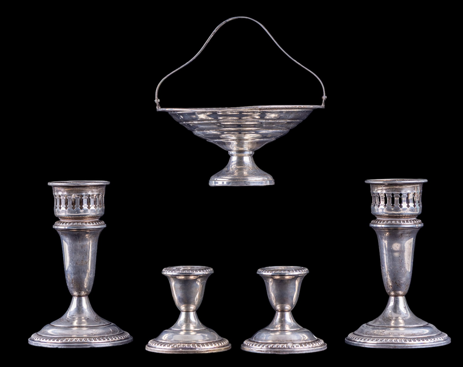 Sterling Silver Basket + 4 Candlesticks: A sterling silver cake basket, a pair of 5 1/2-inch candlesticks with hurricane shade receivers (shades not included), and a pair of smaller candlesticks. All pieces are weighted. One is marked Empire