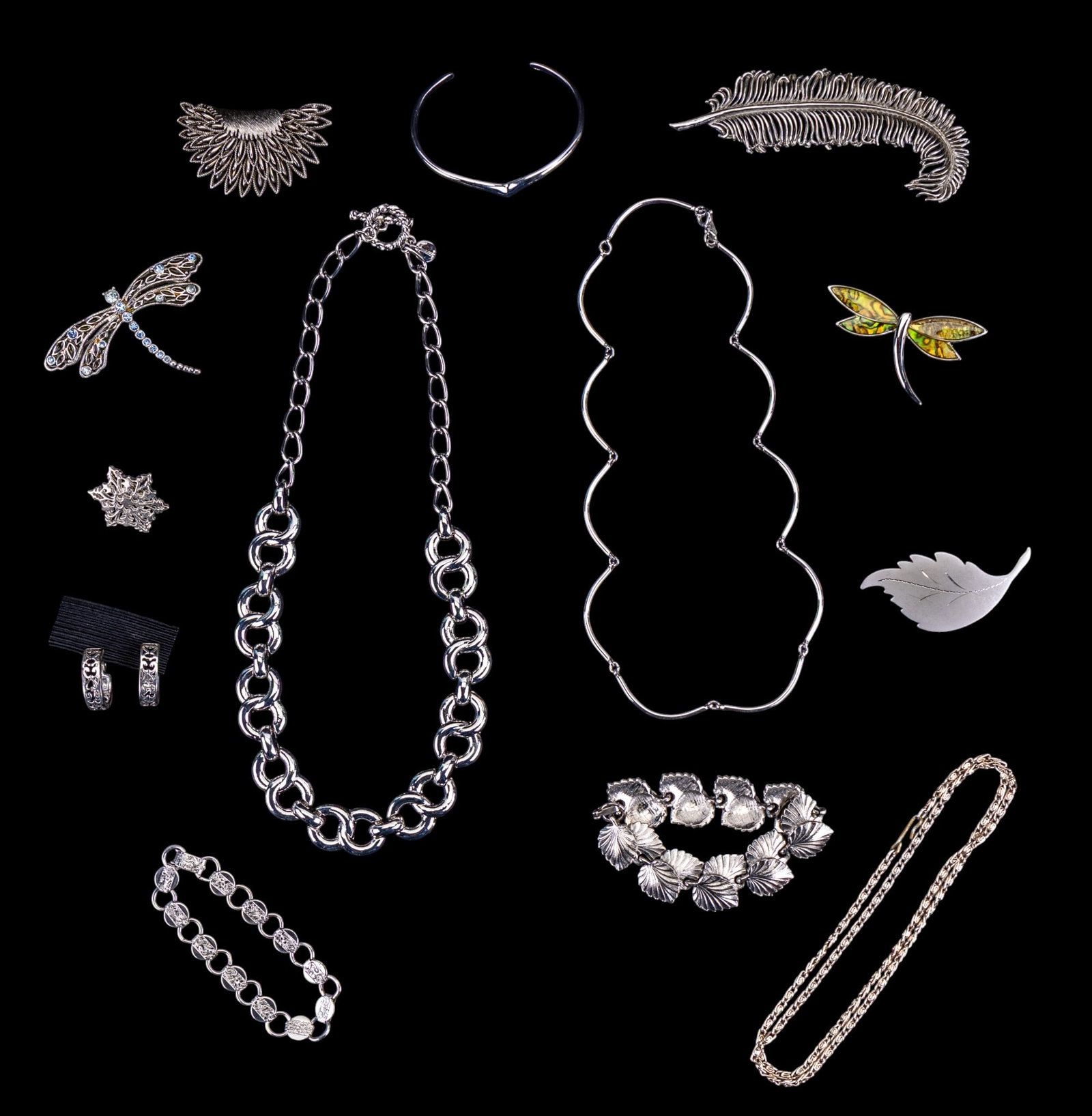 Silver Tone Costume Jewelry: Necklaces, bracelets, pins, and one pair of clip earrings. This silver tone collection features a 4 1/2" Judy Lee feather brooch, a Trifari chain necklace, an Avon chevron cuff from the "Avant" collec