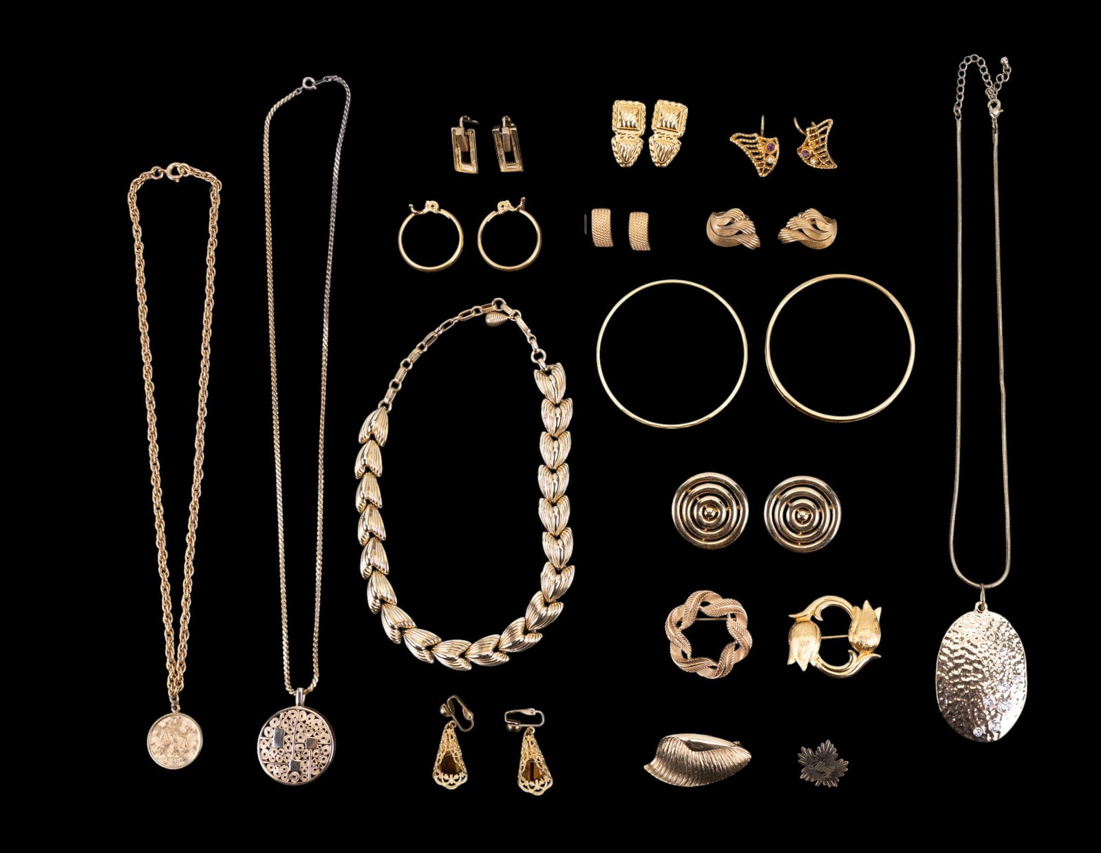 Gold Tone Name Brand Jewelry: Gold tone name brand costume jewelry including Trifari (clip earrings and pin), Coro (choker necklace), Monet (bangle, clip and pierced earrings, double lily-of-the-valley pin), Sarah Coventry (neckla