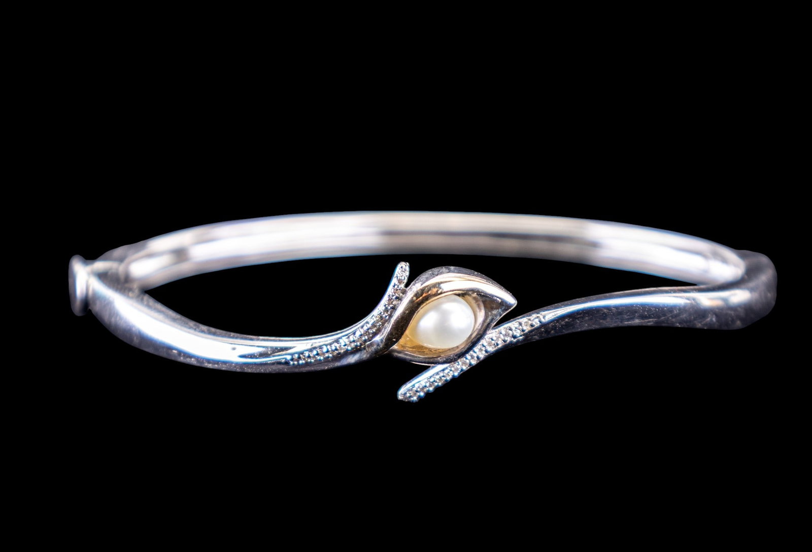 Alwand Vahan Calla Lily Bracelet: A calla lily styled bangle bracelet by Alwand Vahan with a center pearl with flanking diamonds. This sterling silver and 14K gold accent bracelet has a side hinge closure. (16.12 g)