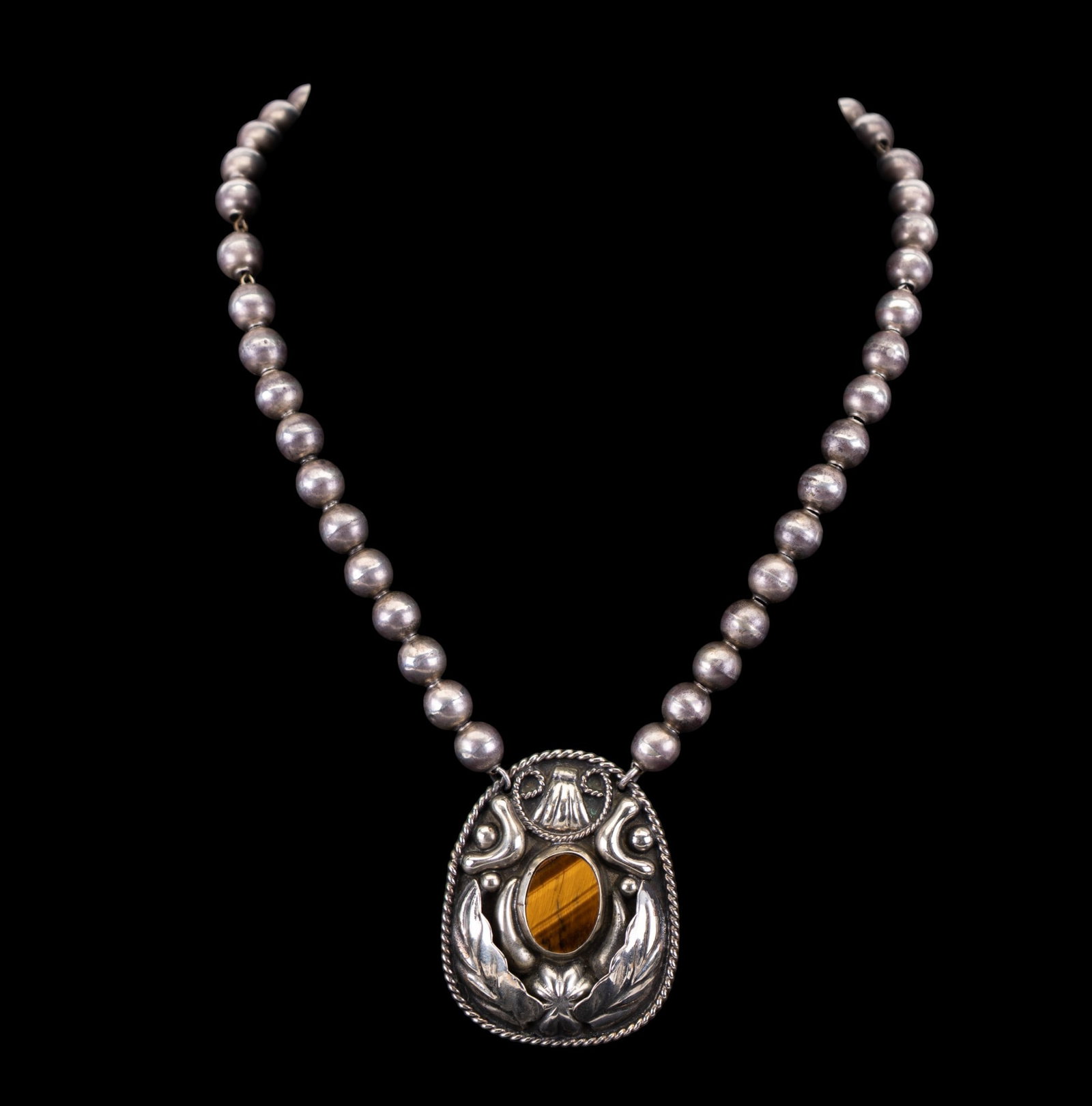 Silver Ball Necklace Tiger Eye Alpaca Pendant: A Mexican silver ball (hollow round beads) necklace on chain featuring an Alpaca marked concho pendant with tiger's eye stone, measures approx. 8" on the drop. Approx weight 29 grams with stone. Hook 