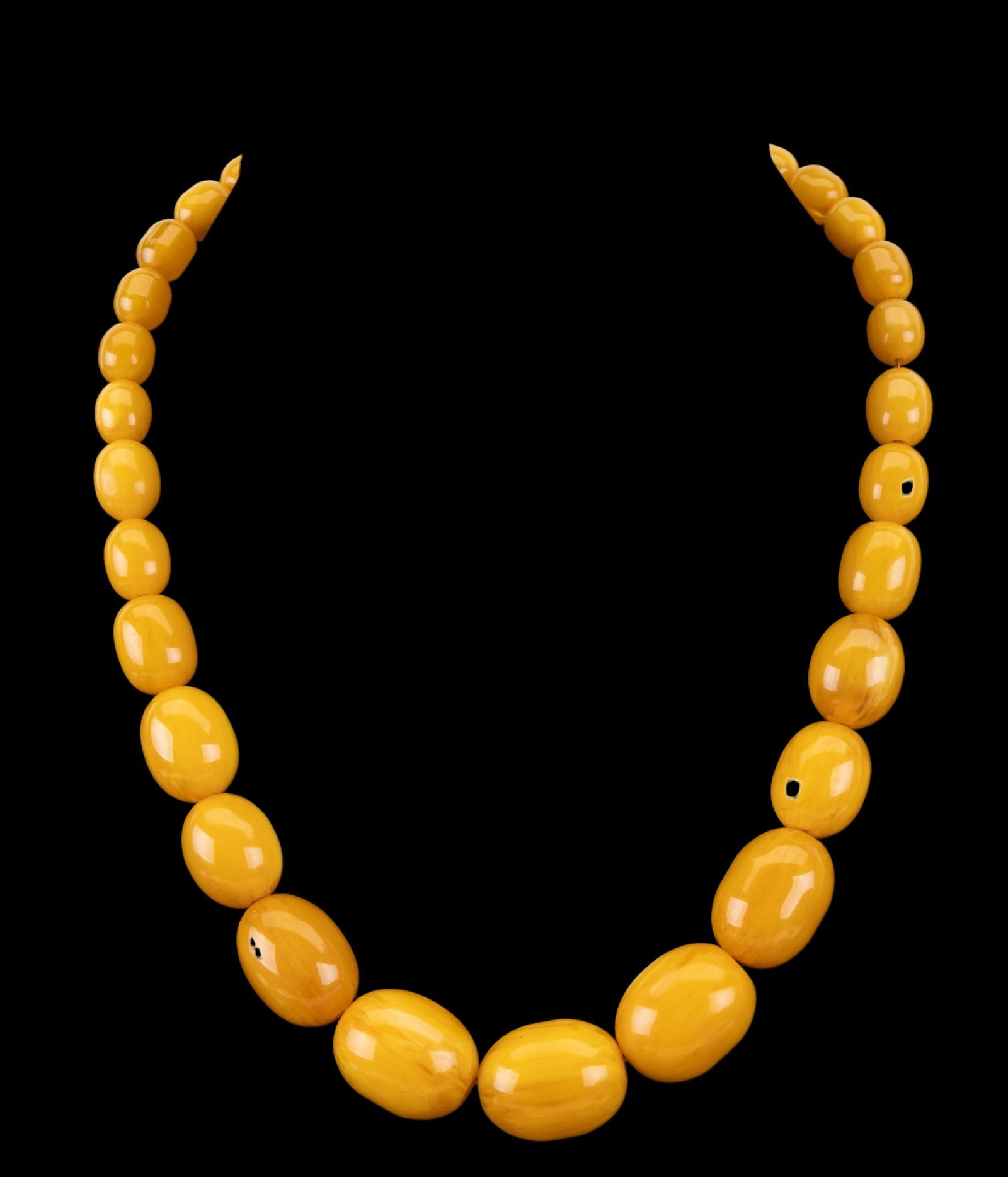 Graduated Bakelite Bead Necklace: A butterscotch colored Bakelite graduated bead necklace with 18K gold plated clasp, measures approx. 8.5" on the drop.