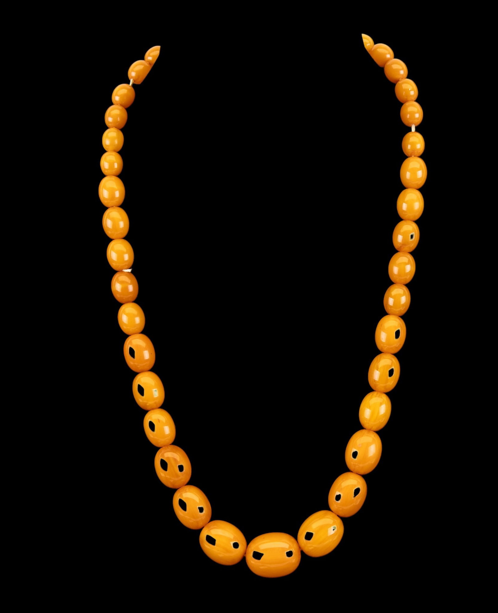 Graduated Bakelite Bead Necklace: A butterscotch colored Bakelite graduated bead necklace with barrel clasp, measures approx. 11" on the drop.