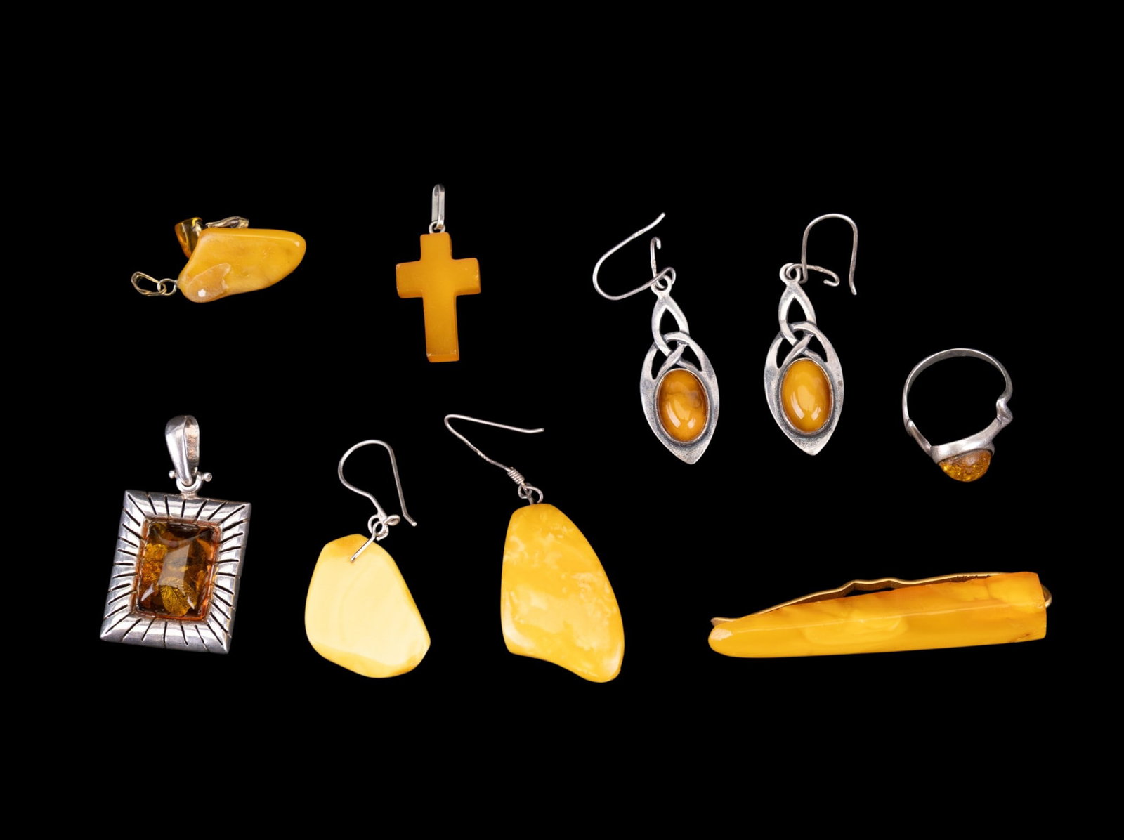Amber and Sterling Jewelry: A collection of sterling silver and amber jewelry including a ring with amber cabochon, size 5.5, a rectangular reconstituted amber pendant, an amber Cross pendant, a butterscotch amber hair pin, Celt