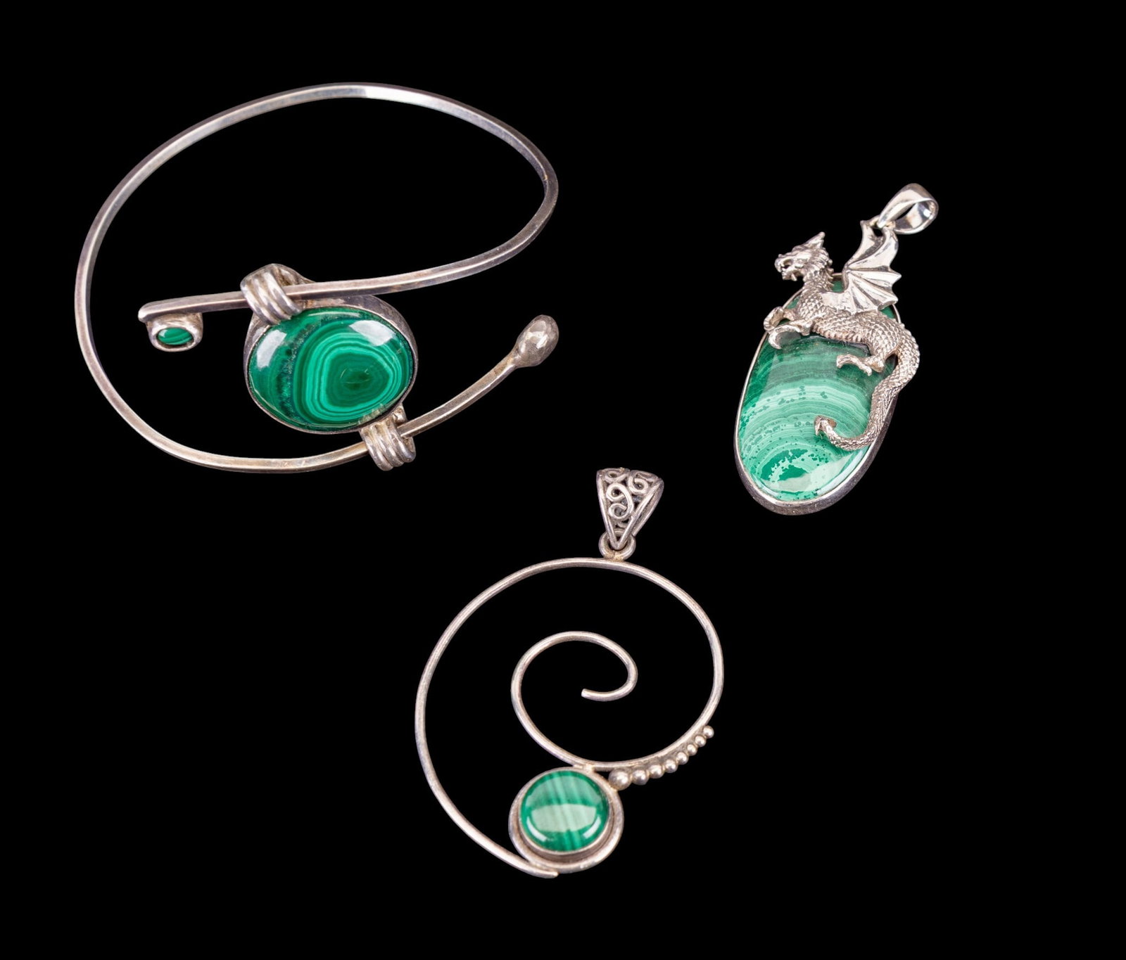 Sterling Silver Jewelry w/ Malachite Stones: A collection of sterling silver and malachite jewelry including a cinching bangle bracelet with large cabochon, an artisan swirl motif pendant with cabochon, and a silver European dragon oval malachit