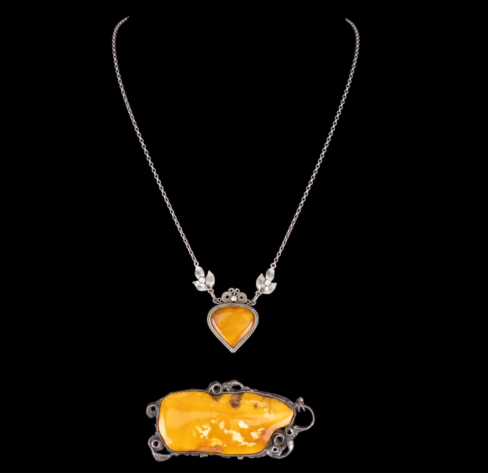 Antique Art Nouveau Amber and Sterling Jewelry: An Art Nouveau large natural butterscotch egg yolk colored amber pendant approx. 3.5" L, and an Art Nouveau filigree sterling and amber leaf motif and rhinestone pendant necklace, measures approx. 10"
